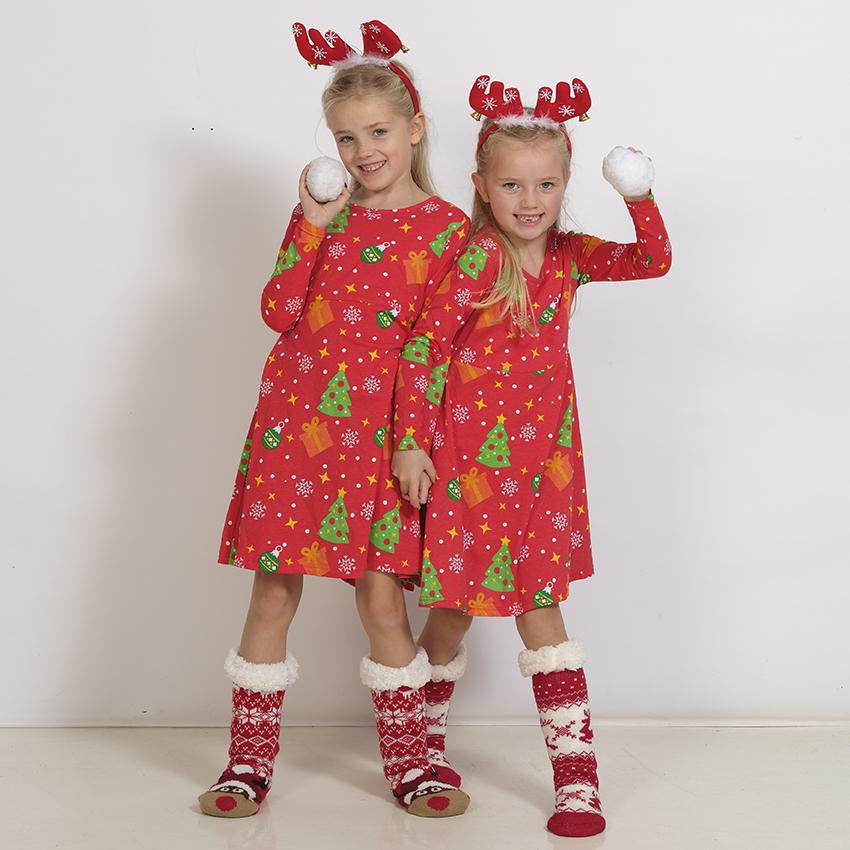 Deux enfants portant des robes de Noël rouges.