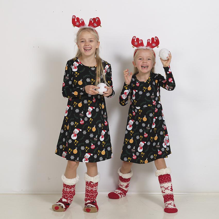 Deux enfants portant des robes de Noël noires.