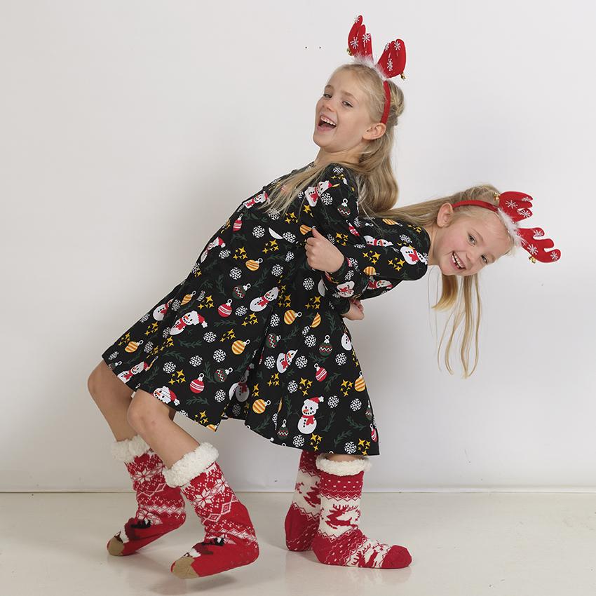 Deux enfants enjoués portant des robes de Noël noires.