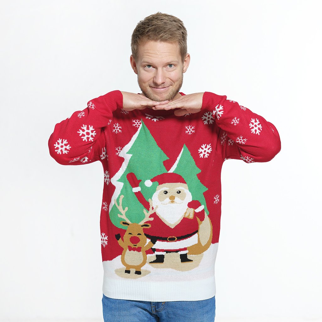 Un homme posant avec un pull de Noël rouge avec Rudolph et le Père Noël dessus.