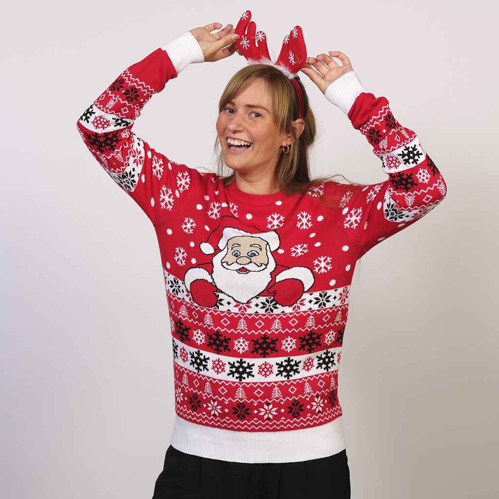 Une femme portant un pull de Noël rouge avec le Père Noël et des flocons de neige.