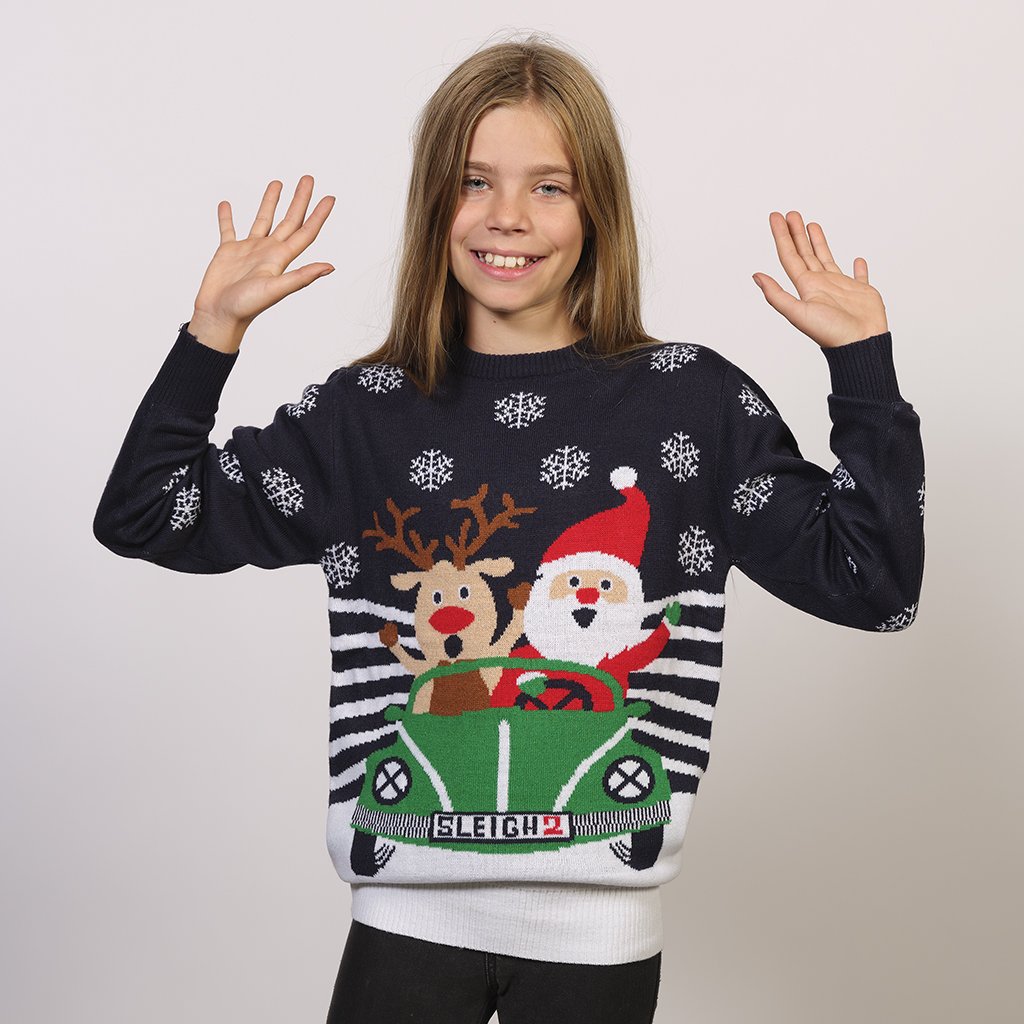 Un enfant portant un pull bleu de Noël avec Rudolph et le Père Noël dans une voiture.