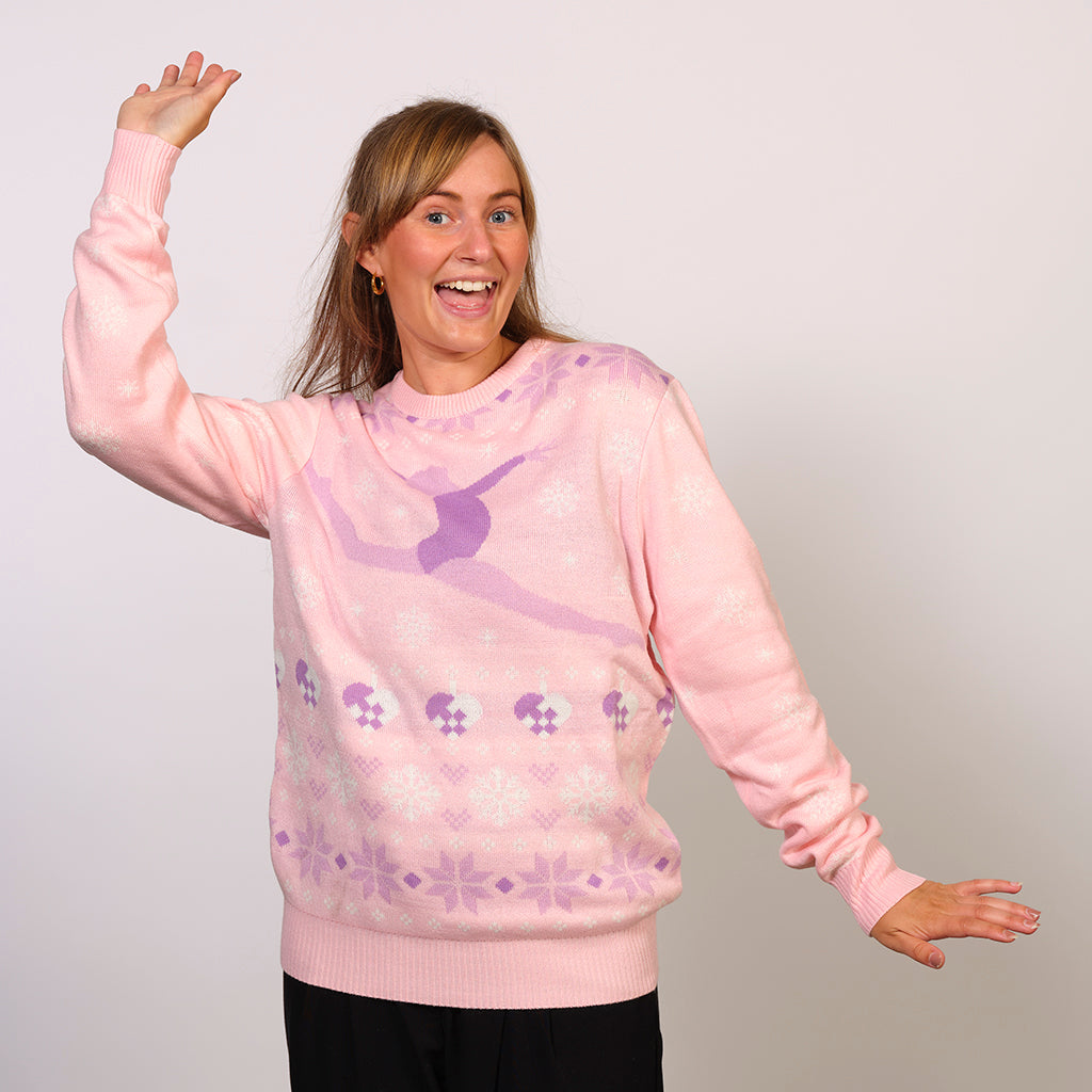 En danskede kvinde smiler, mens hun står i en lyserød julesweater.