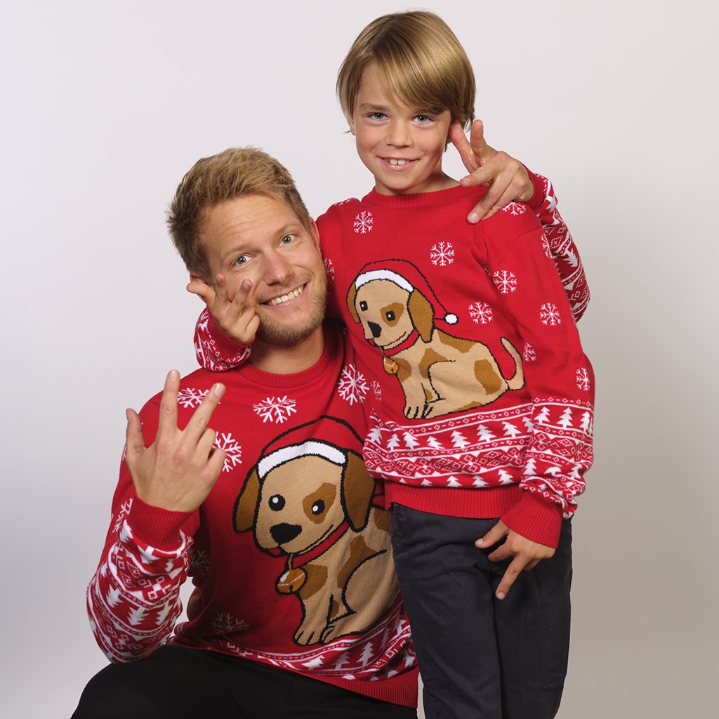 Un homme et un enfant portant un pull rouge de Noël avec un chien et des flocons de neige.