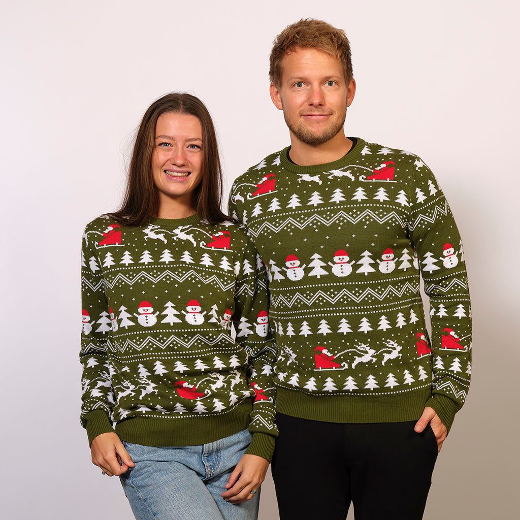 Un couple portant un pull vert de Noël avec des arbres de Noël, des pères Noël et un motif de Noël.
