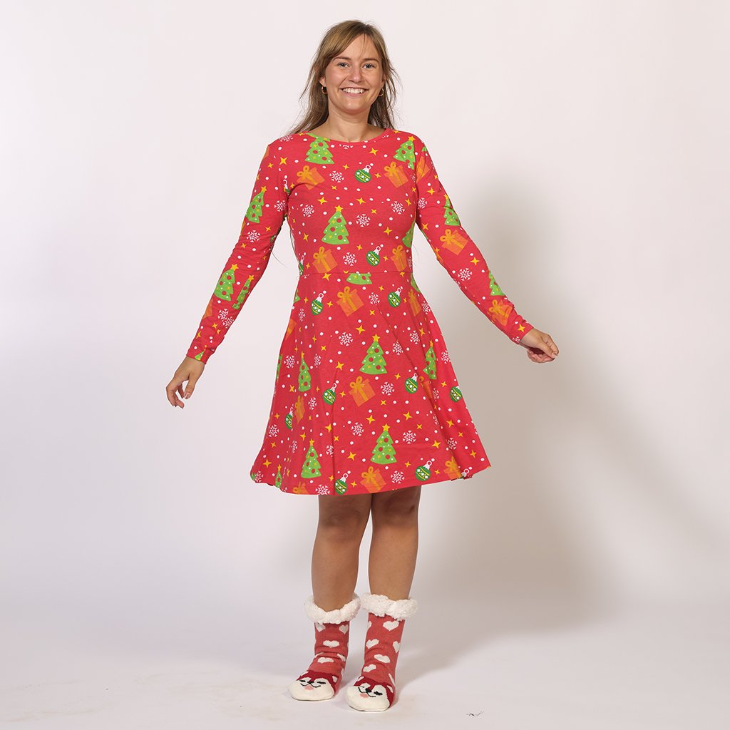 Une femme souriante portant une robe de Noël rouge.