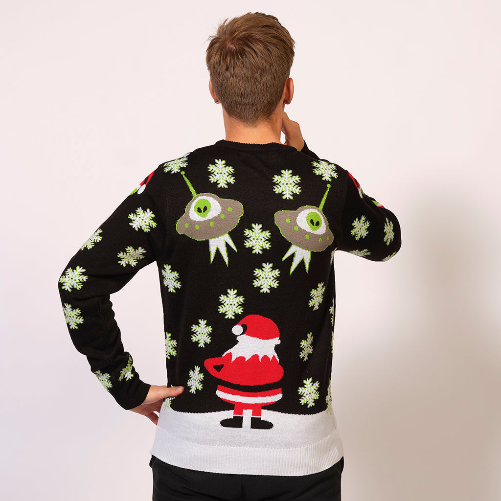 En mand står med ryggen til, hvor man også ser bagsiden af mandens sweater, hvor der ses ufoer og ryggen af en julemand.