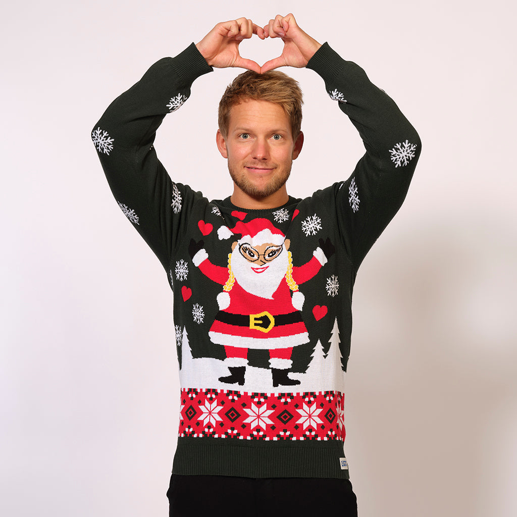 En mand der viser et hjertetegn med hænderne er iført en julesweater.