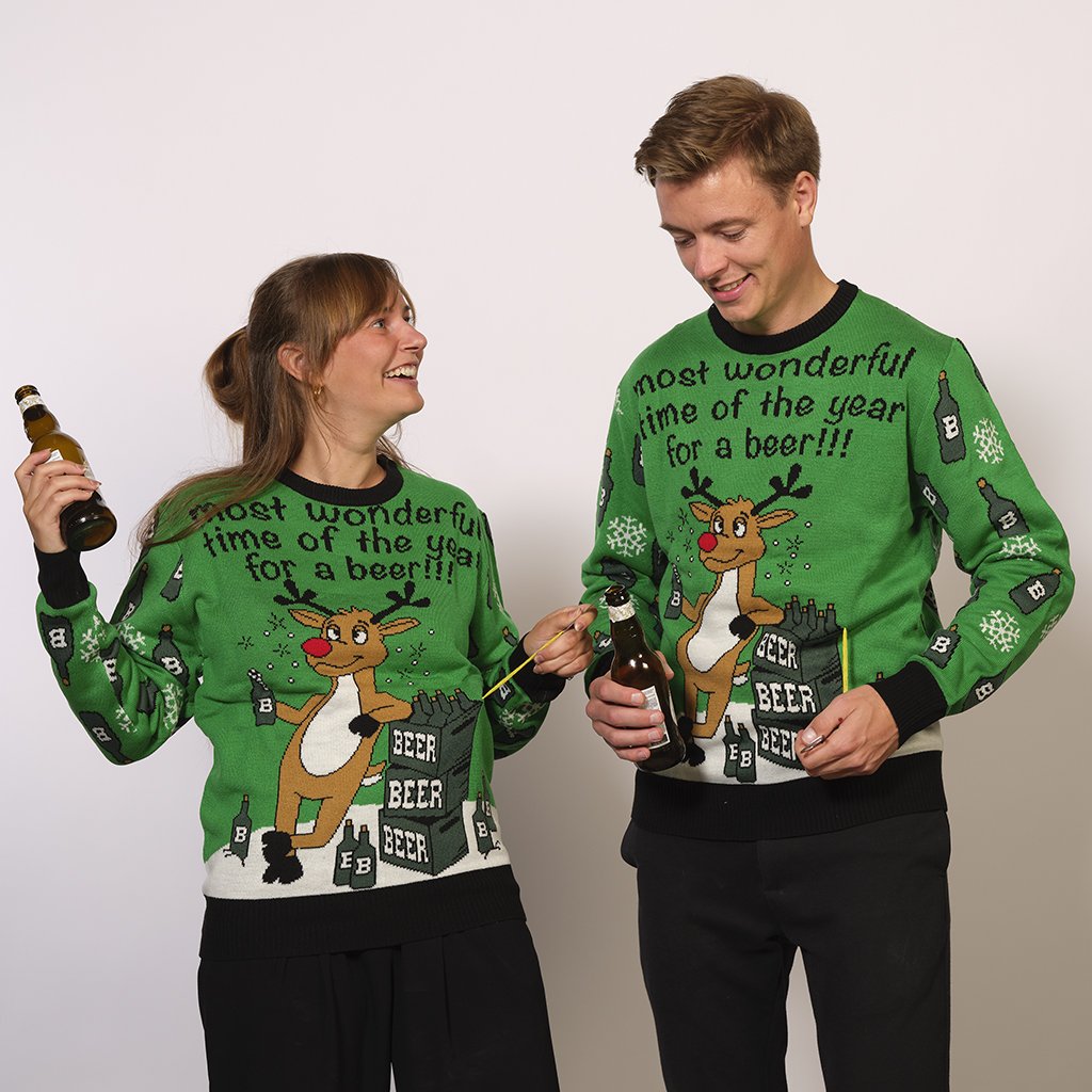 Un couple portant un pull de Noël vert avec la citation 