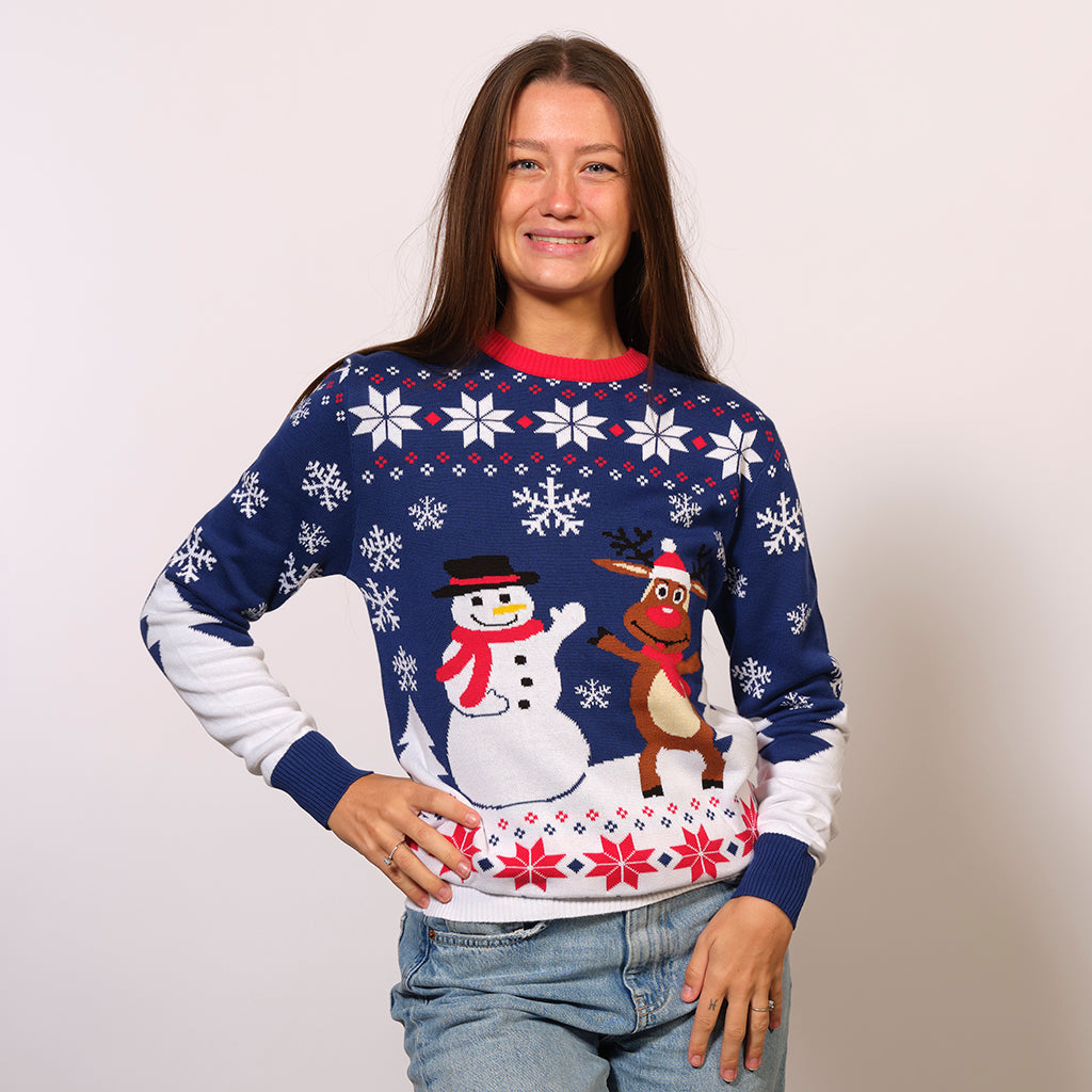 Une femme portant un pull de Noël blanc et bleu avec un bonhomme de neige et Rudolph dessus.
