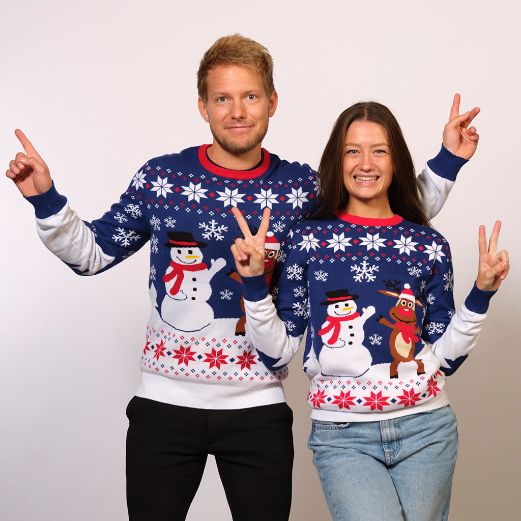 Un couple portant un pull de Noël blanc et bleu avec un bonhomme de neige et Rudolph.