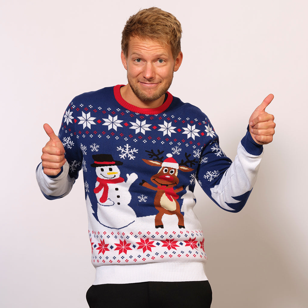 Un homme posant portant un pull de Noël blanc et bleu avec un bonhomme de neige et Rudolph.