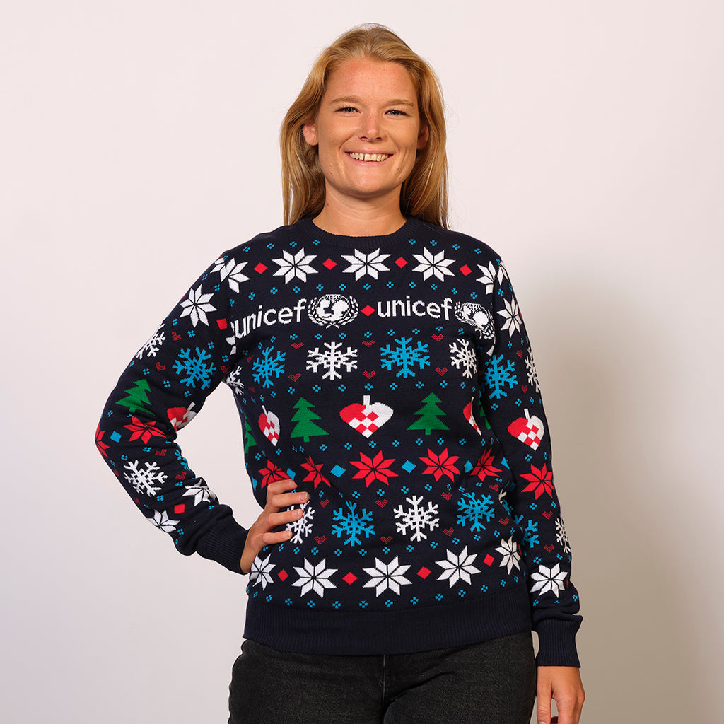 En smilende kvinde iført en Unicef julesweater med snefnug på.