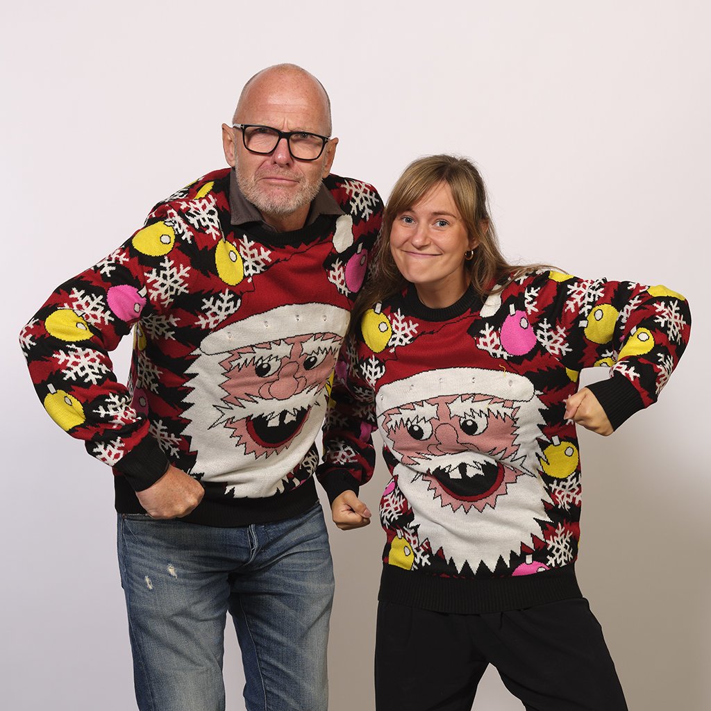 Un homme et une femme portant un pull de Noël rouge et noir avec un Père Noël souriant.