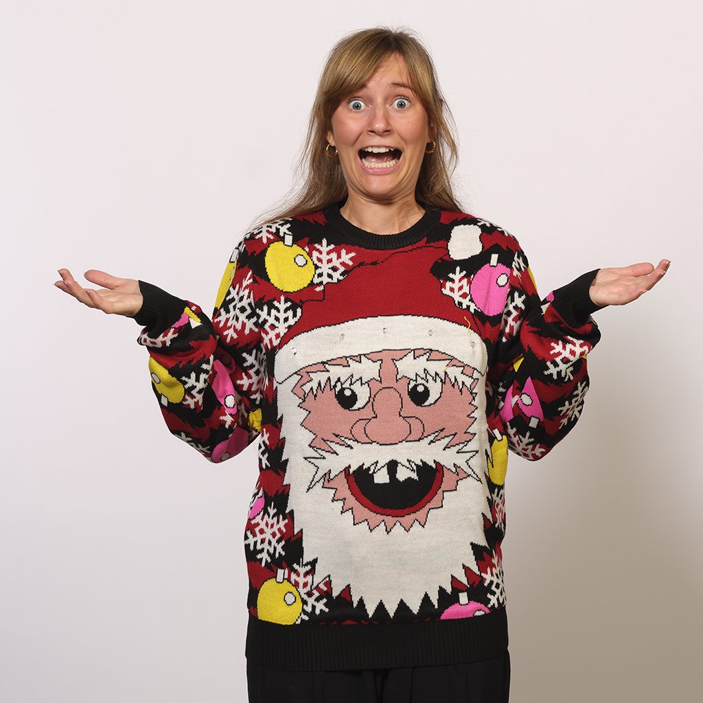 Une femme portant un pull de Noël rouge et noir avec un Père Noël souriant.