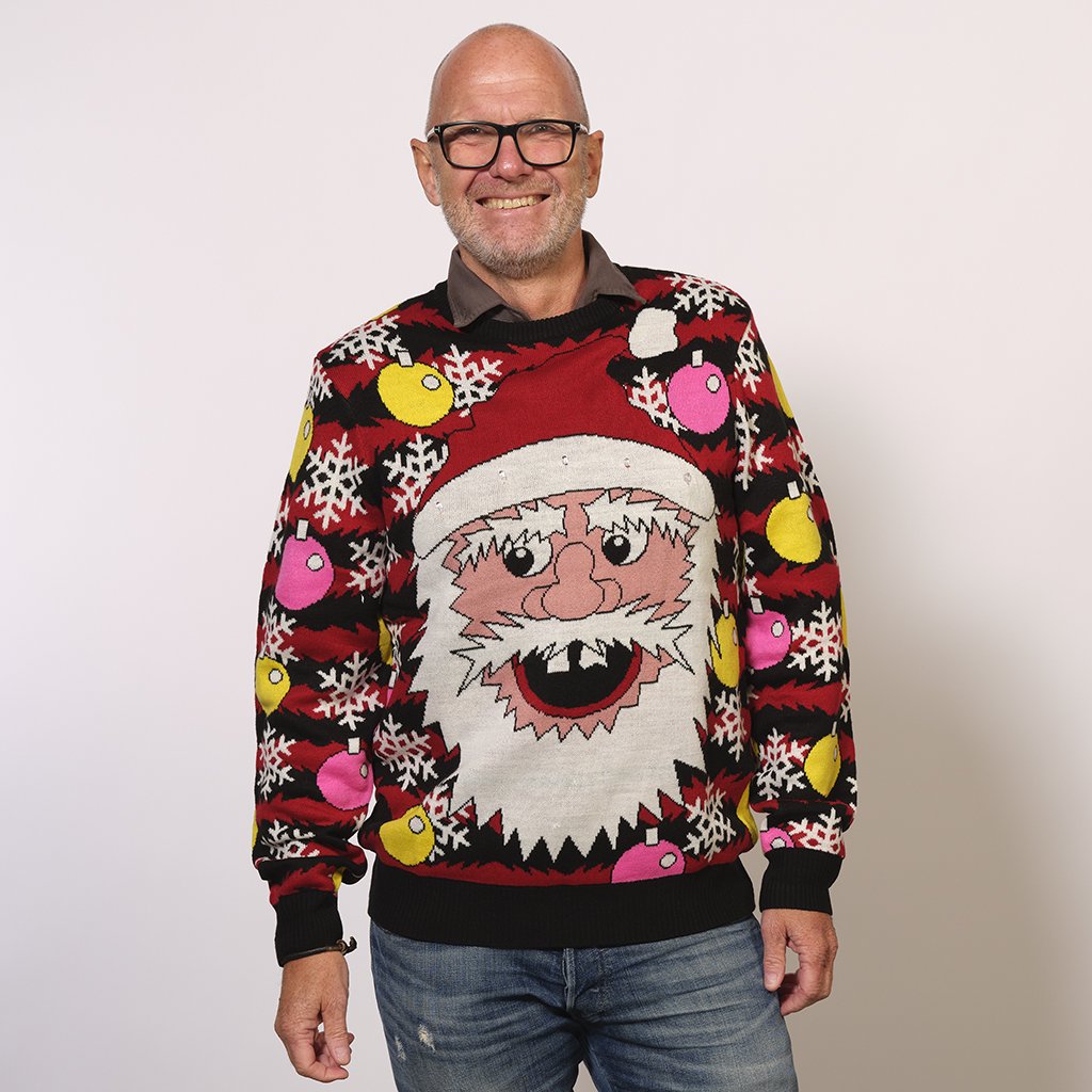Un homme portant un pull de Noël rouge et noir avec un Père Noël rieur.