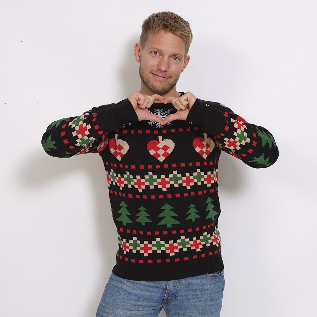 Un homme posant avec un pull noir imprimé Noël.