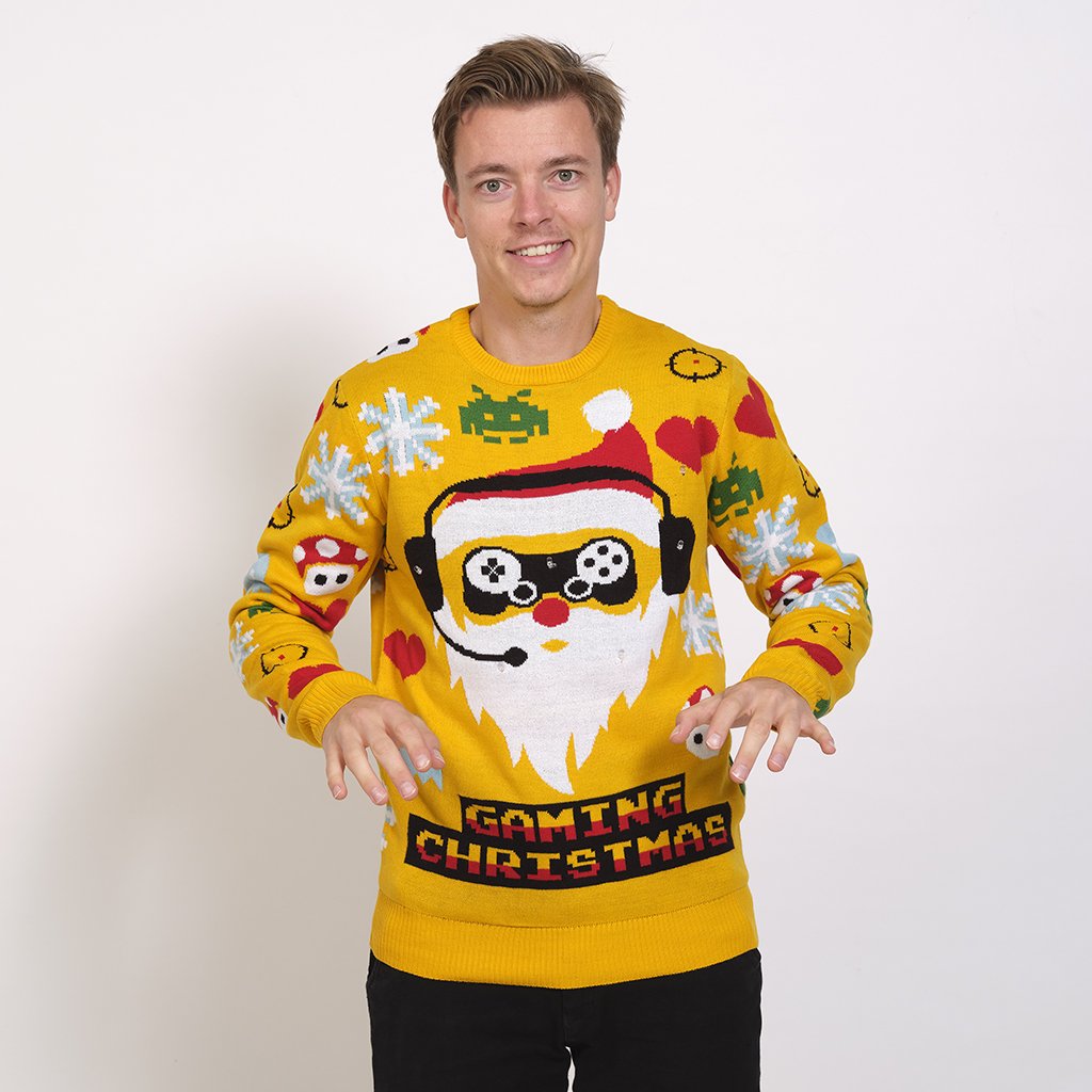 Un homme portant un pull de Noël jaune avec un lutin joueur dessus.