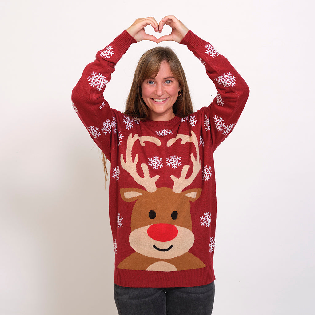 Une femme portant un pull de Noël rouge foncé avec Rudolph et des flocons de neige.