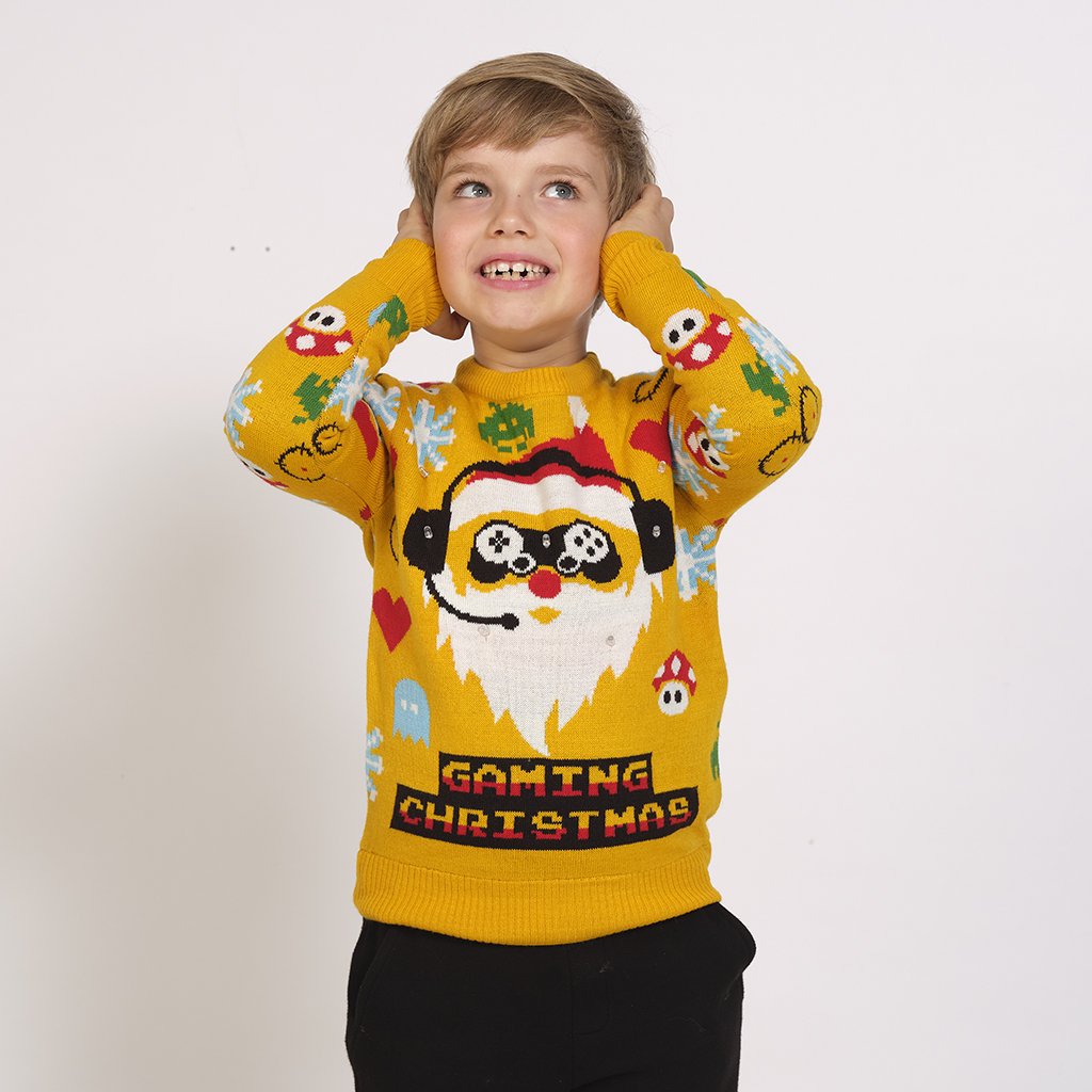 Un enfant portant un pull jaune de Noël avec un lutin joueur dessus.
