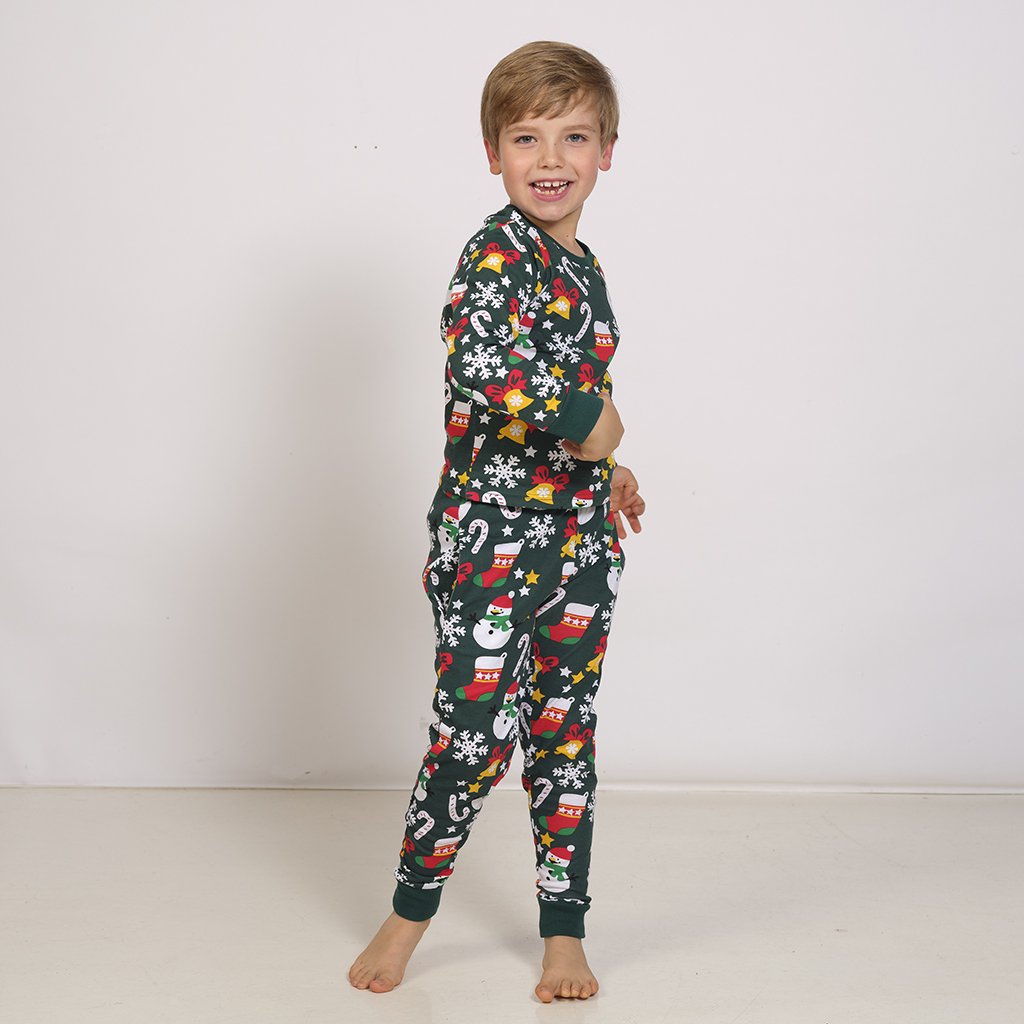 Un enfant portant un pyjama de Noël vert avec un imprimé de Noël.