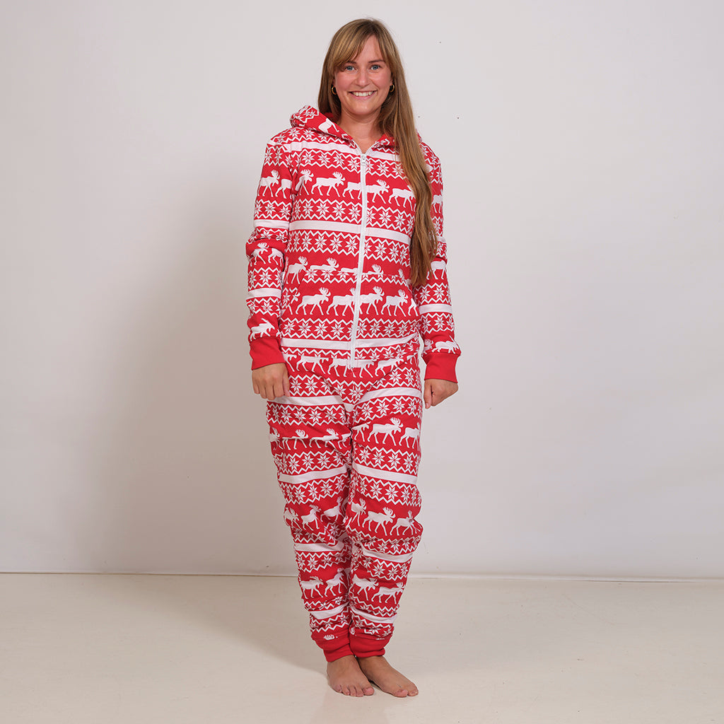 En dame poserer i et rødt julejumpsuit.