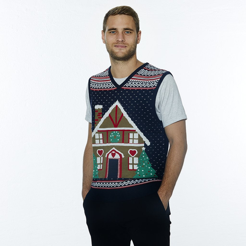 Un homme portant un gilet de Noël orné d'une maison en forme de gâteau.