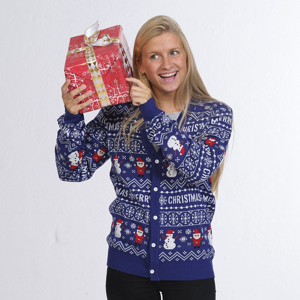 Une femme posant avec un gilet de Noël bleu avec des elfes et des bonshommes de neige.