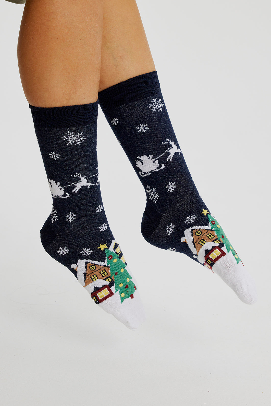 Een paar voeten met kerstsokken met een besneeuwde stad erop.