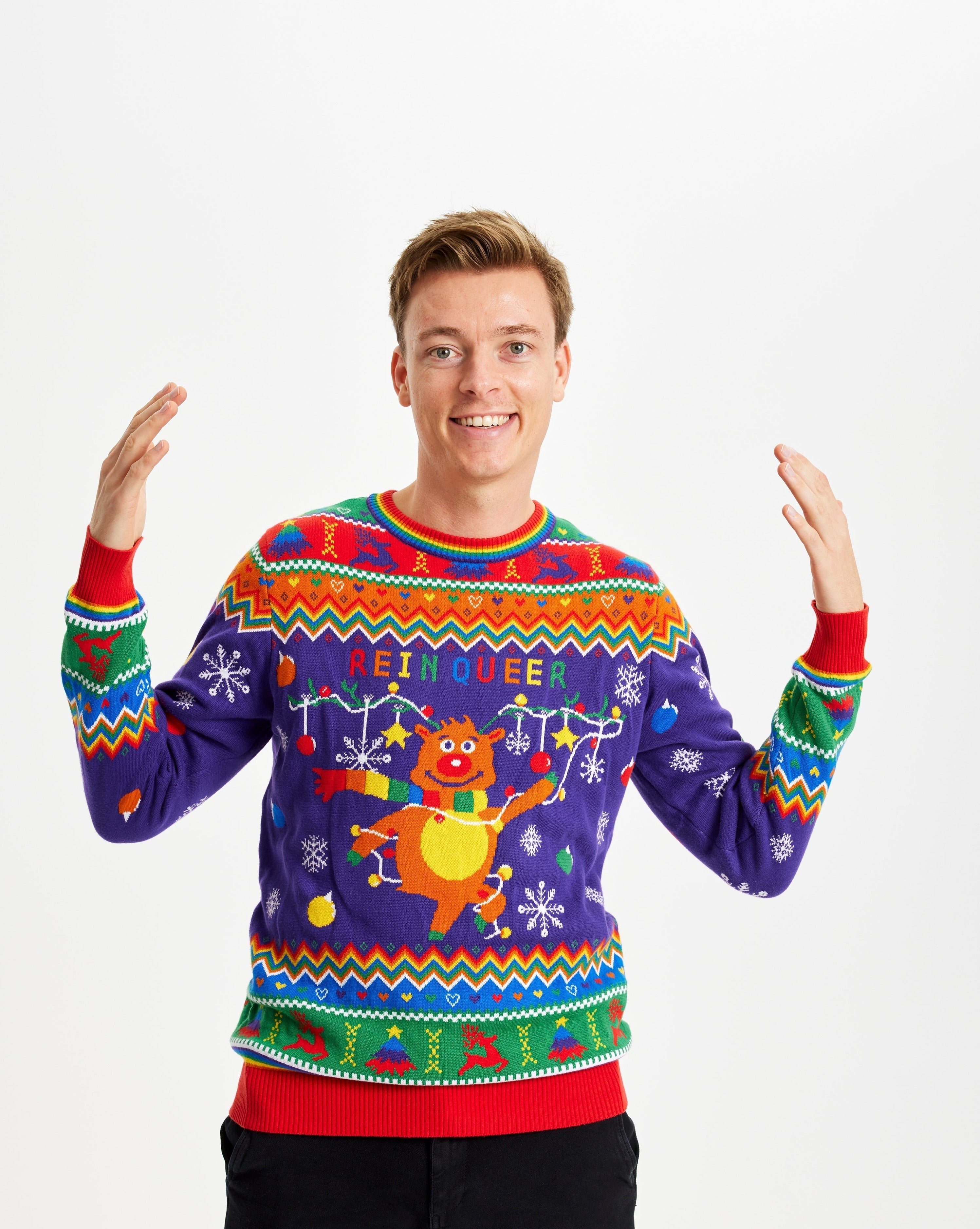 Een man draagt een regenboogkleurige kersttrui met de quote "Rein queer".