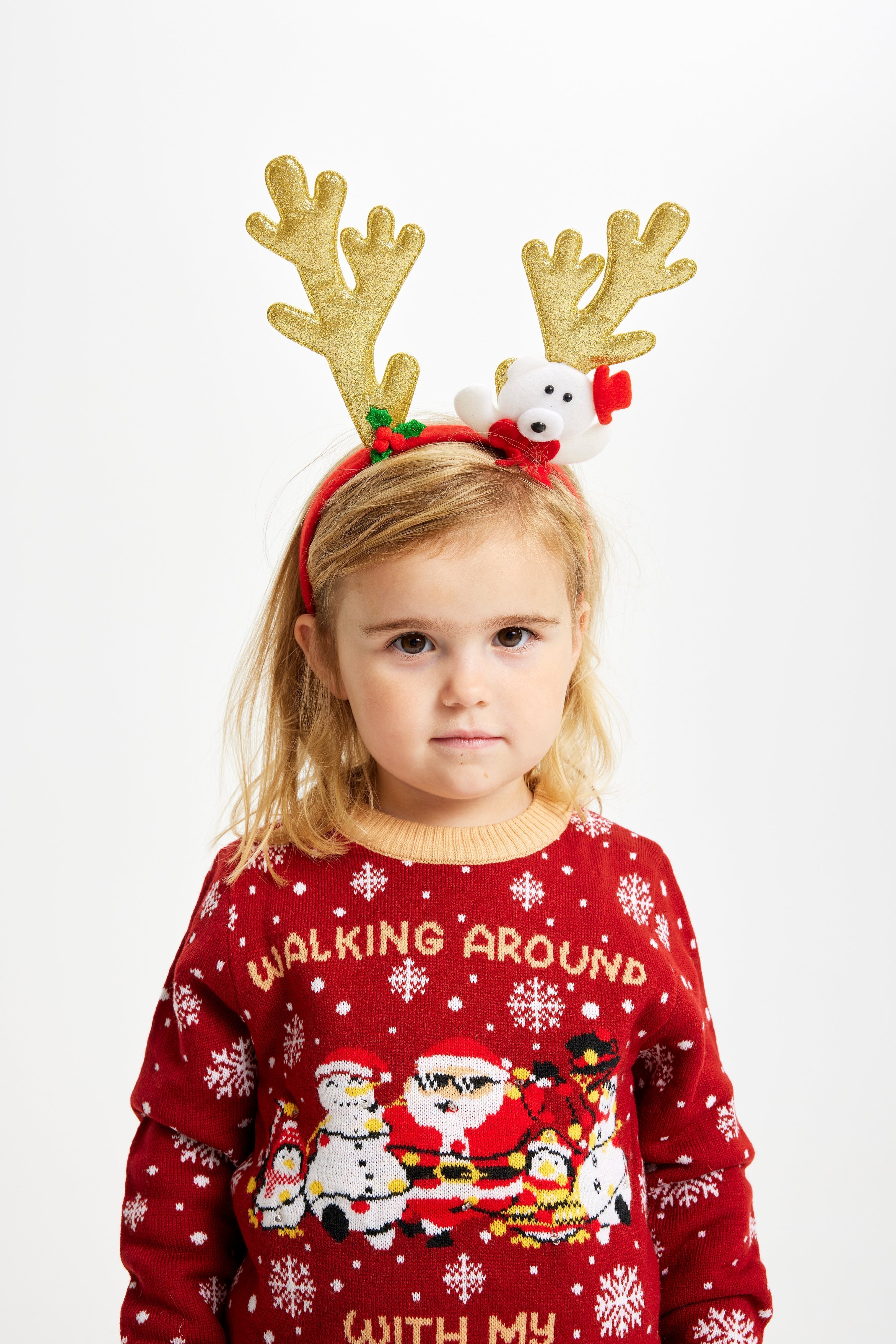 Un enfant en bas âge portant un pull de Noël rouge avec l'inscription 