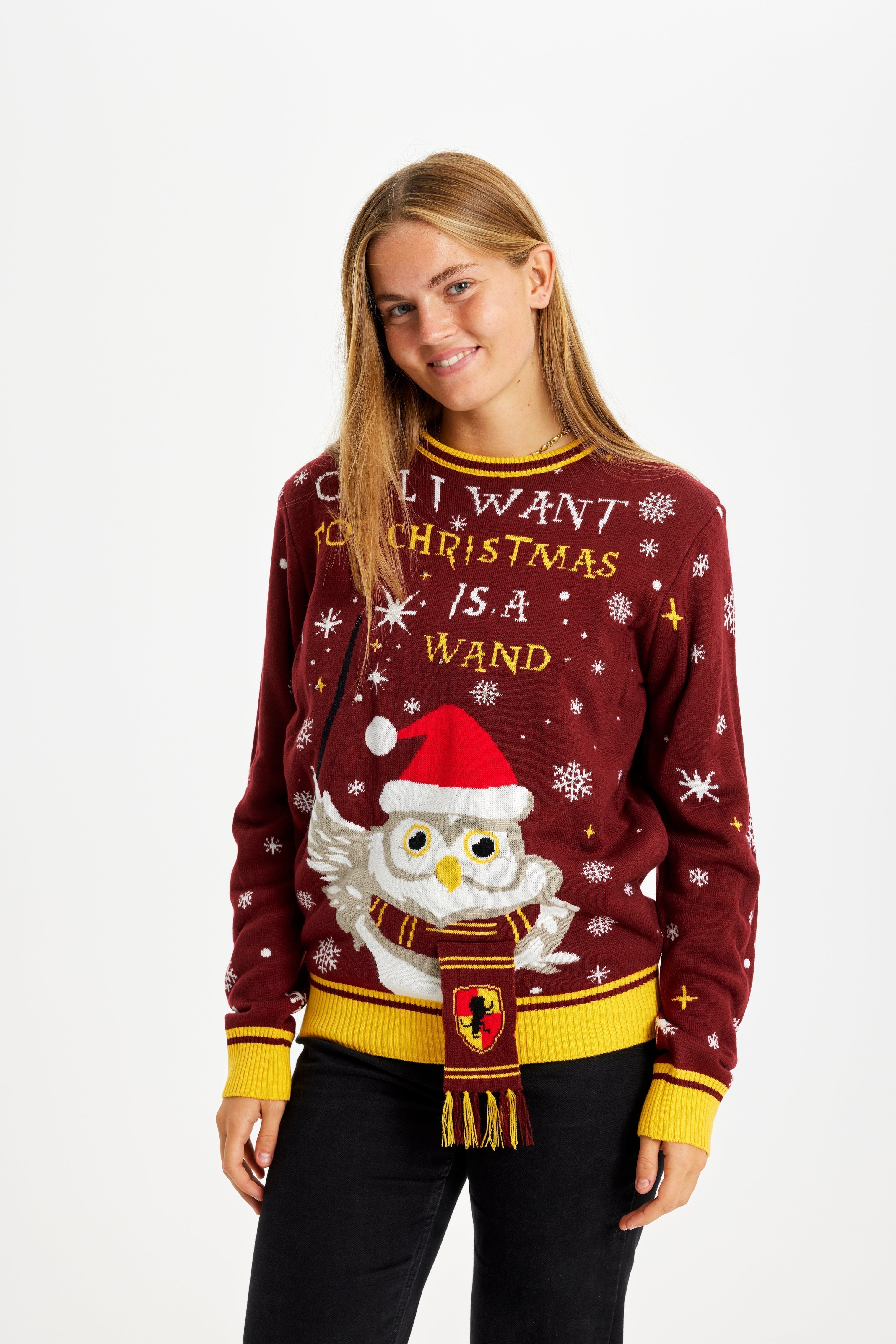 Une femme souriante portant un pull de Noël rouge avec la citation 