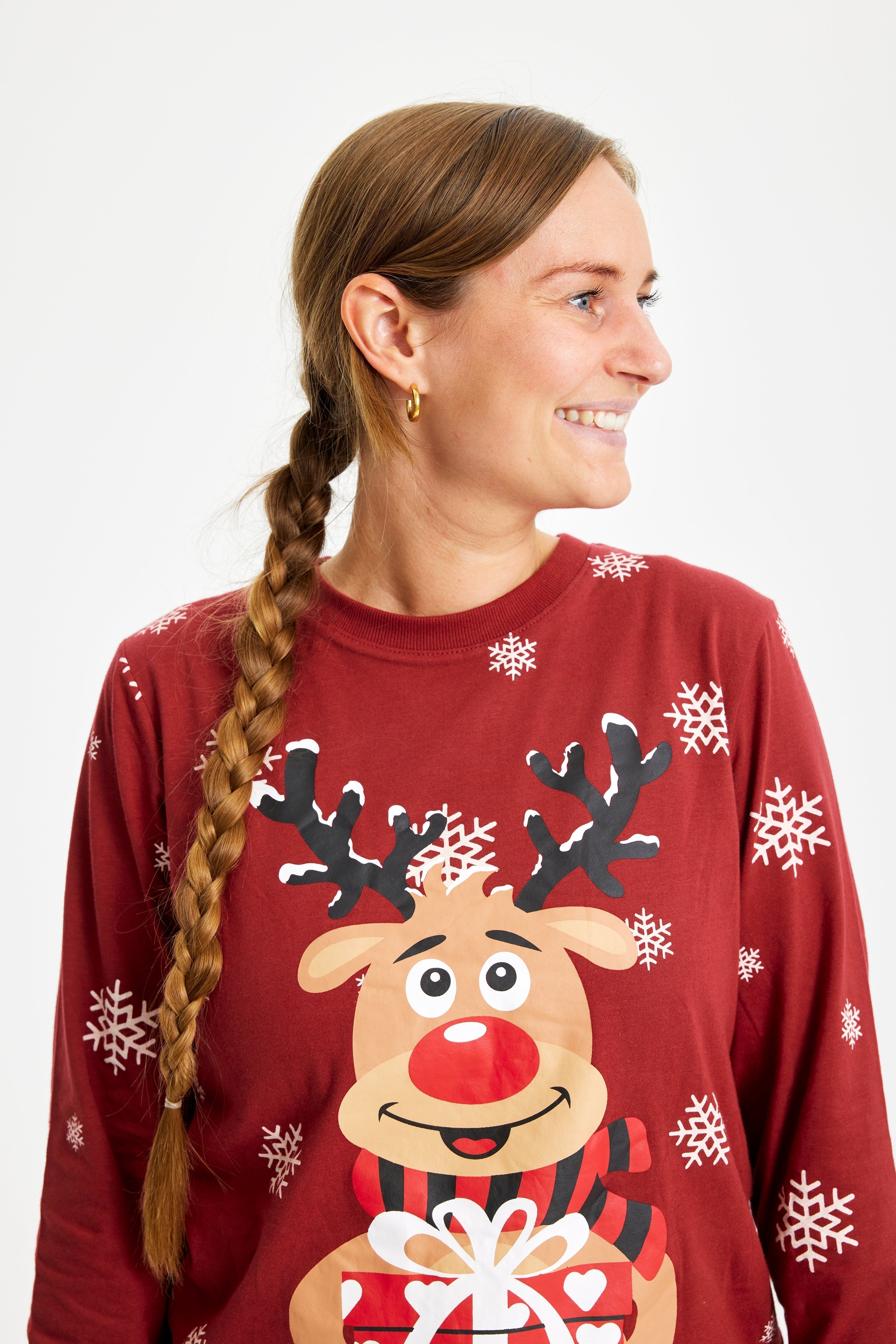 Une femme souriante portant un pyjama de Noël rouge avec Rudolph.