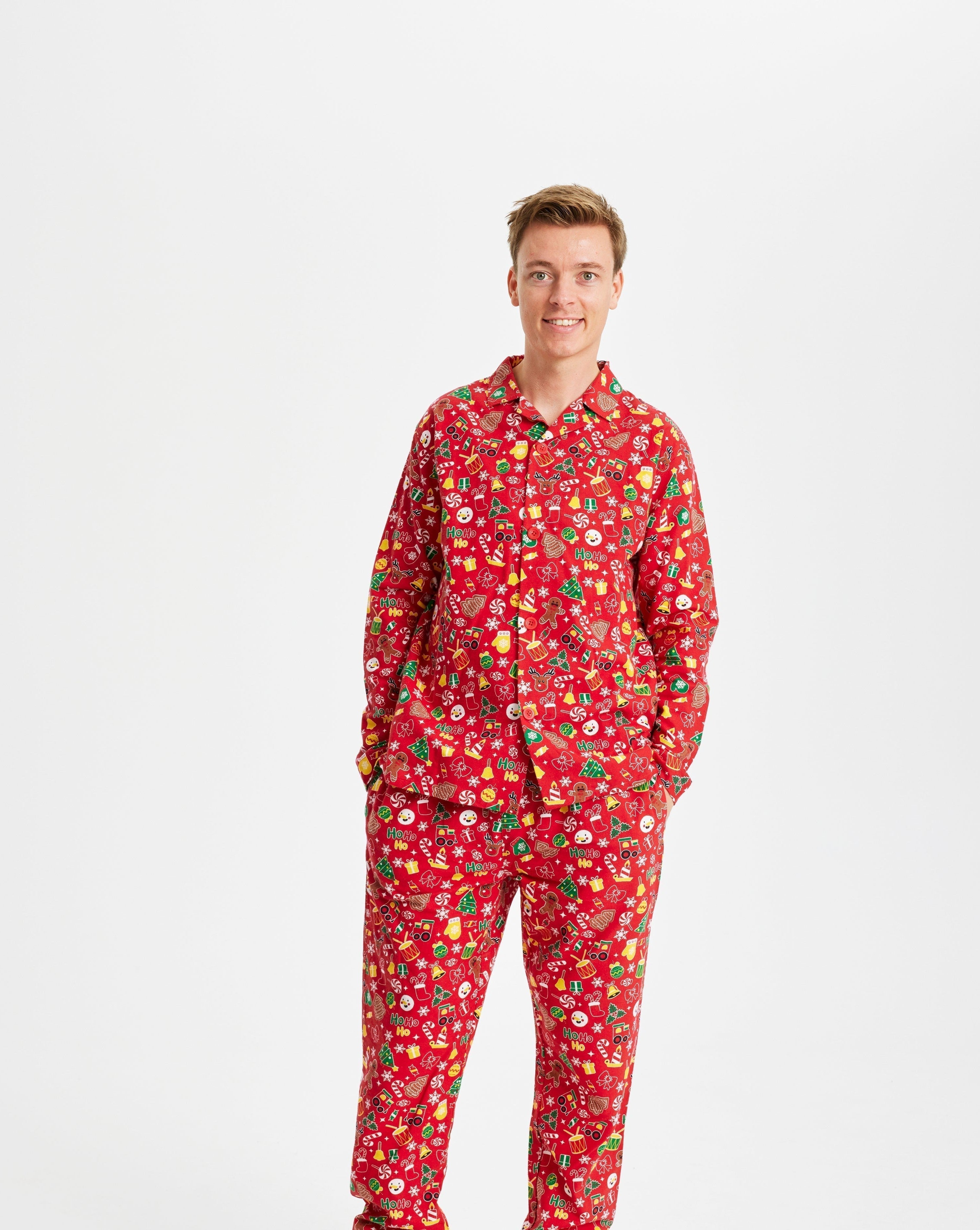 Un homme souriant portant un pyjama de Noël rouge avec un imprimé de Noël.