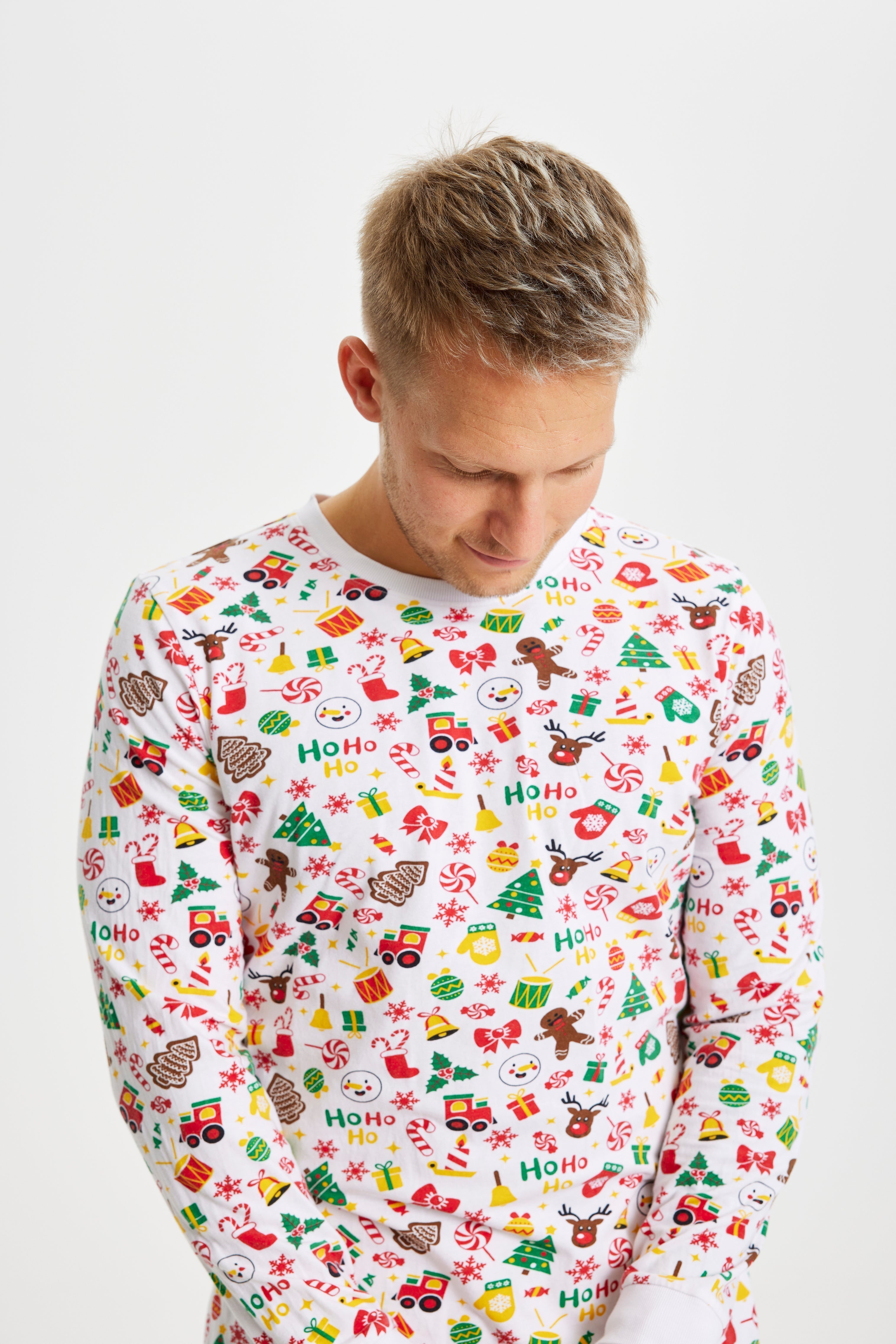 Un homme regardant vers le bas portant un pyjama de Noël blanc.