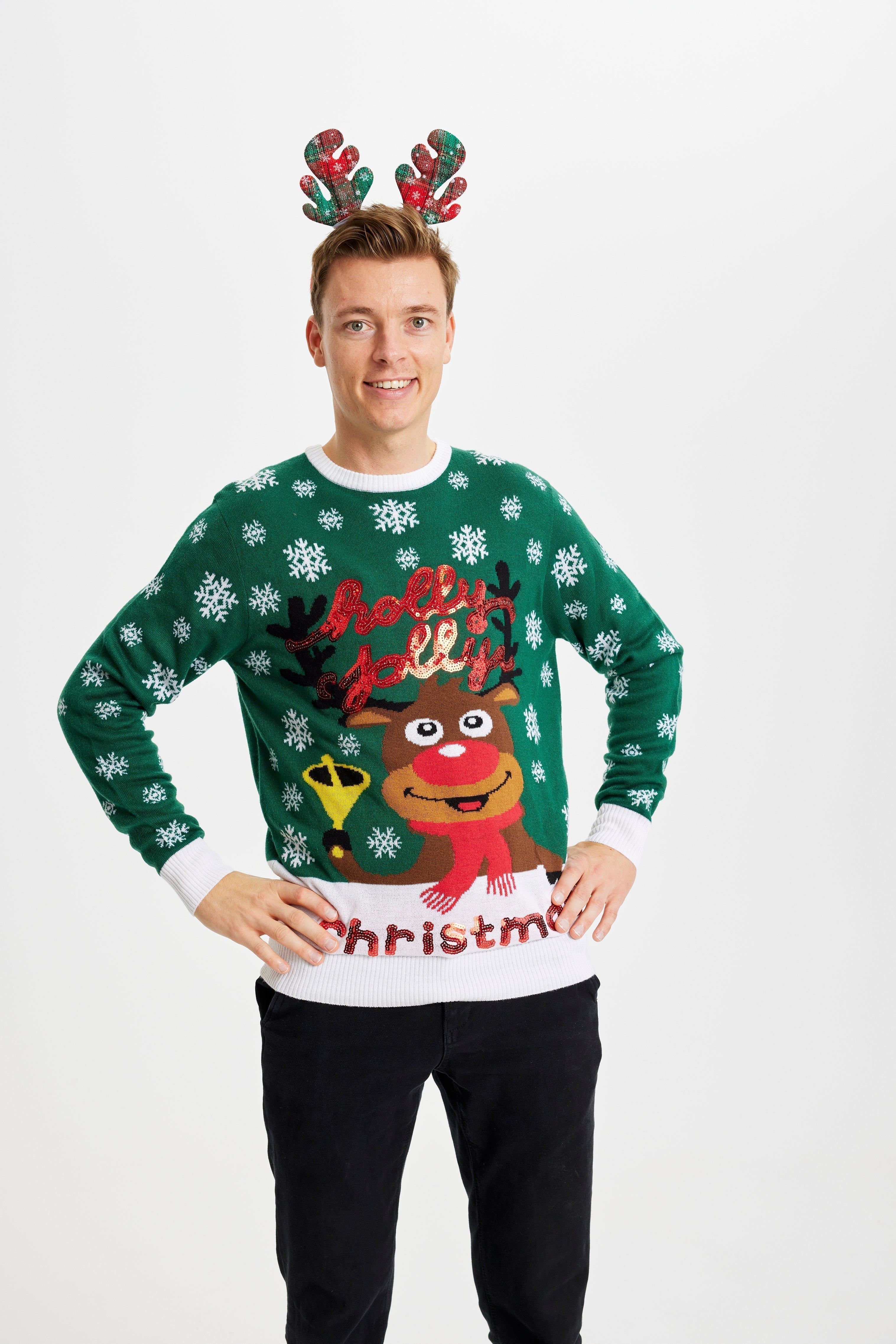 Un homme qui pose, portant un pull vert de Noël avec Rudolph.