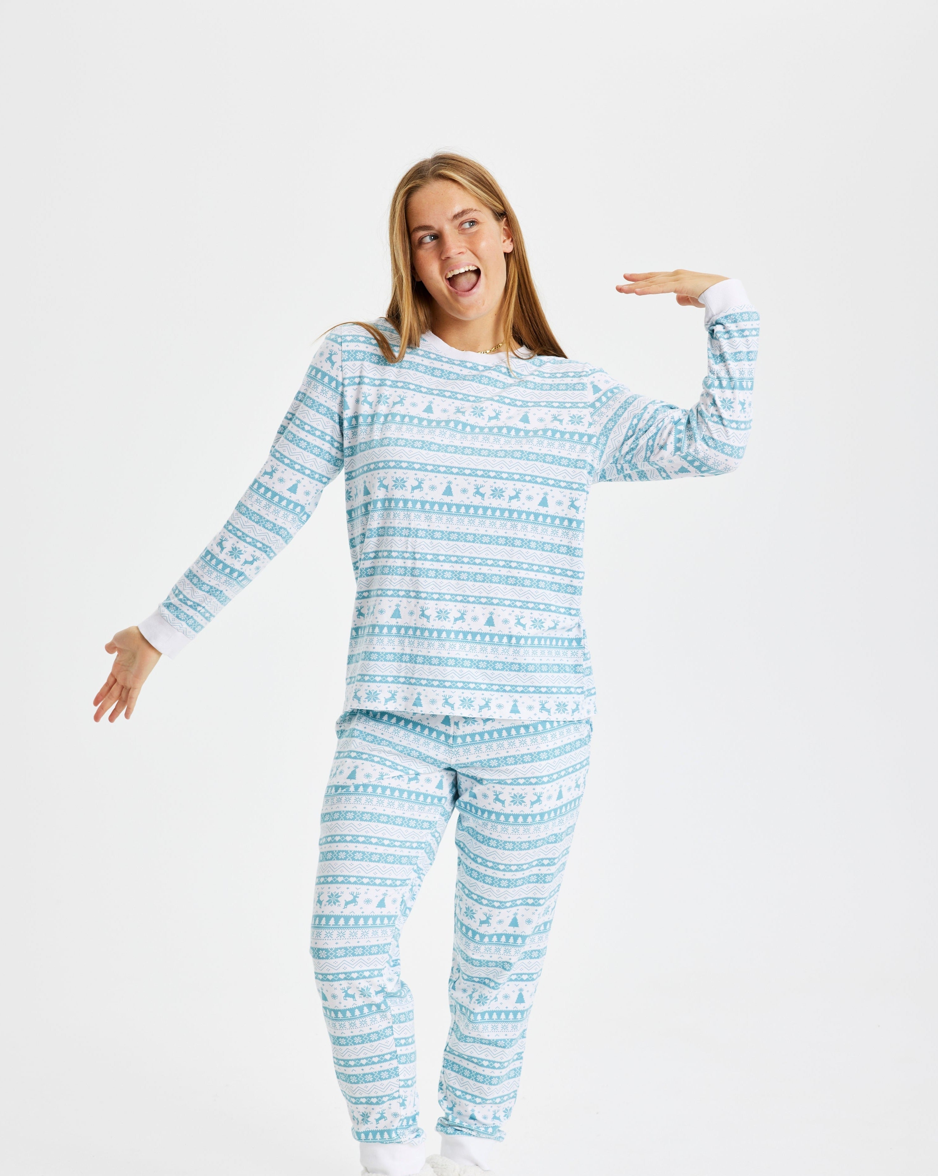 Une femme qui bâille, vêtue d'un pyjama de Noël bleu clair.