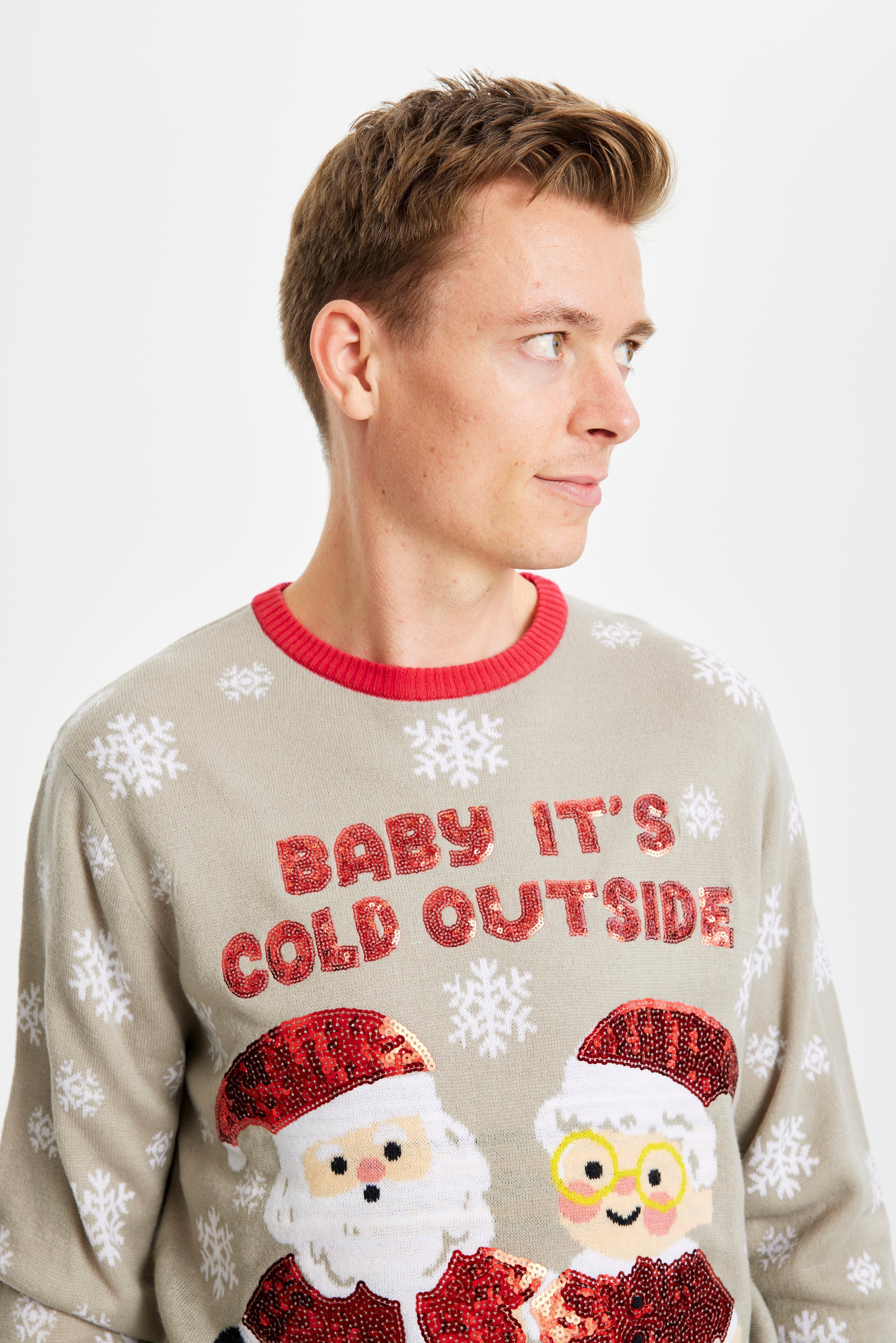 Un homme portant un pull de Noël gris avec la citation 