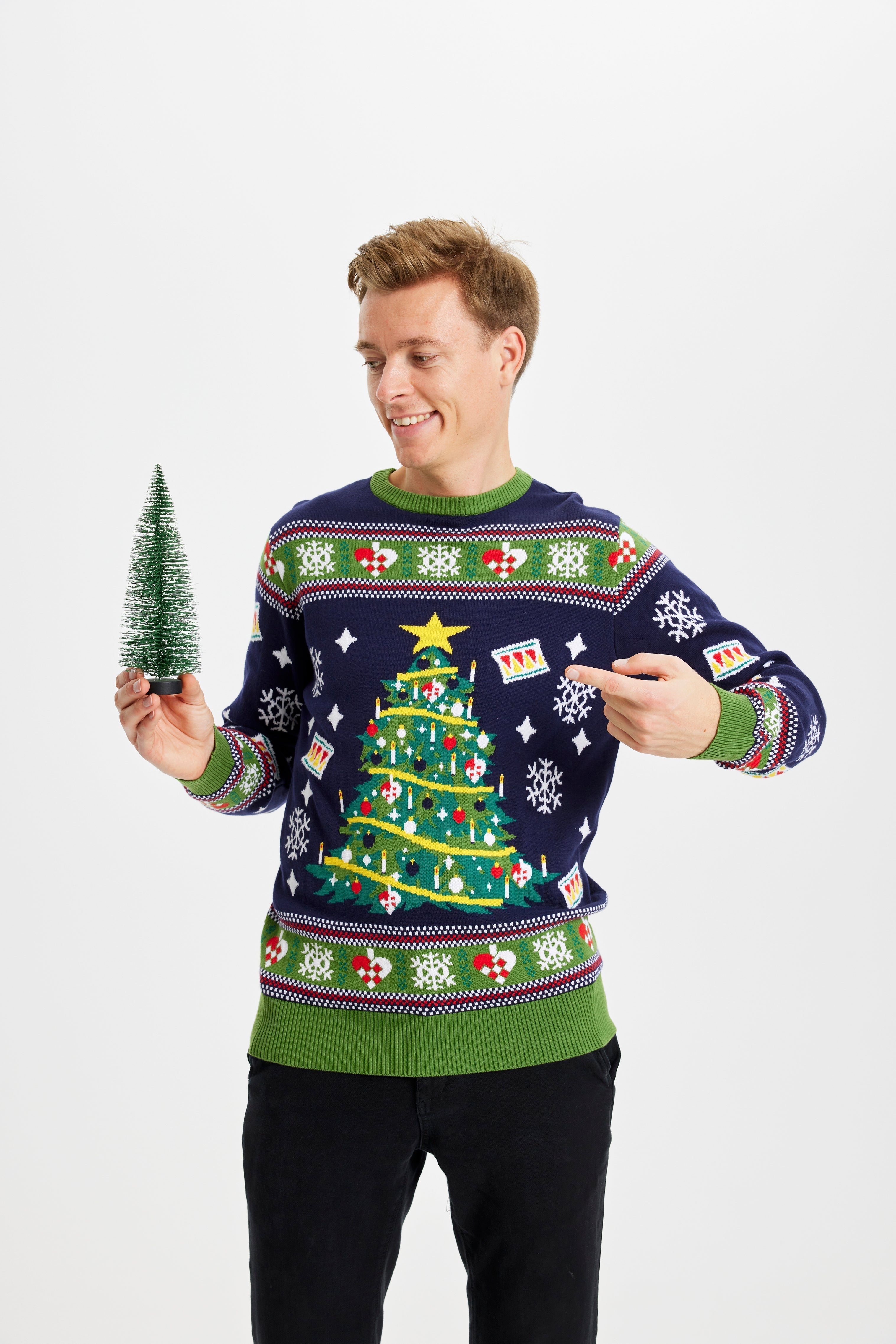 Un homme avec un sapin de Noël portant un pull bleu et vert avec un sapin de Noël.