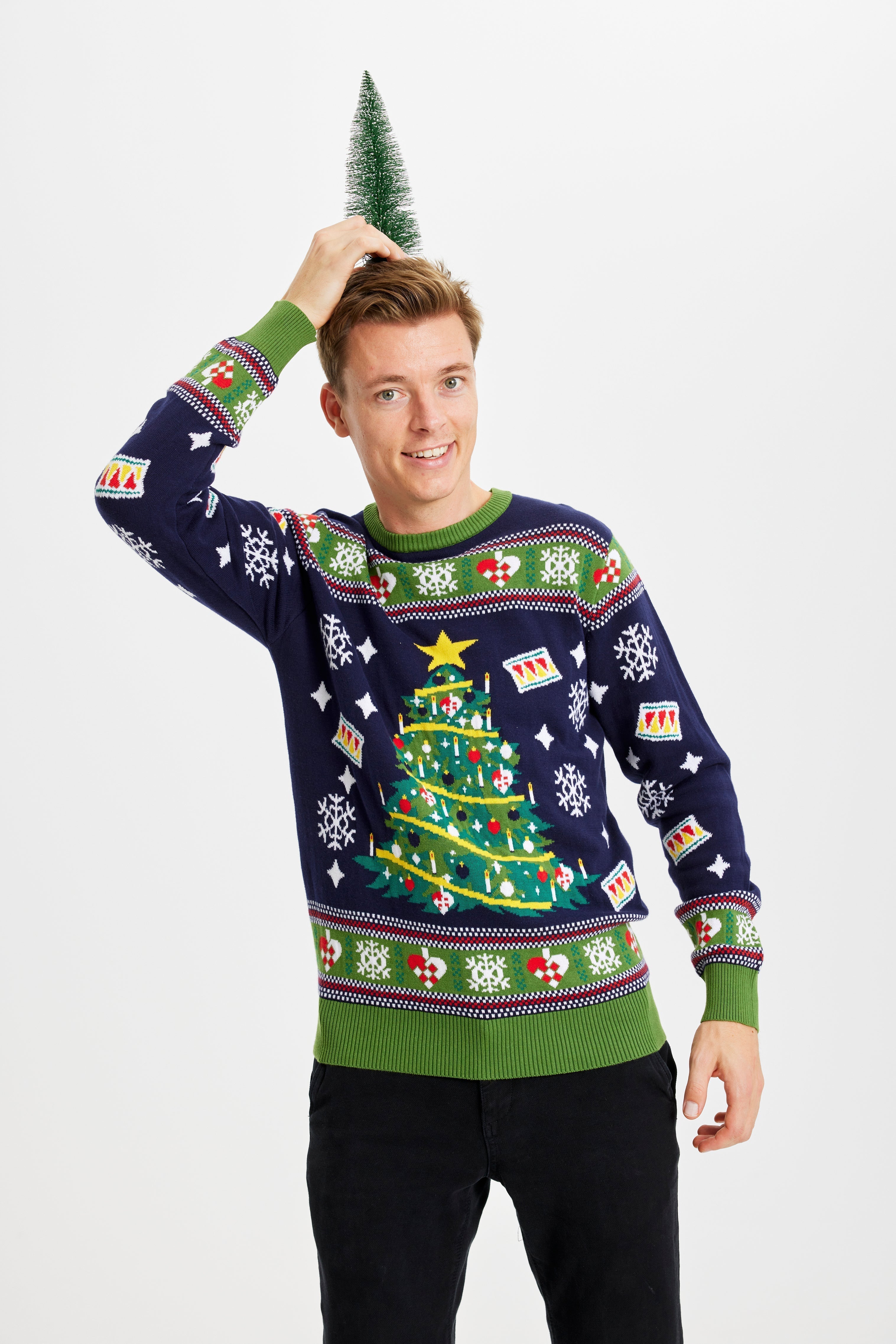 Un homme portant un pull de Noël bleu et vert orné d'un arbre de Noël.