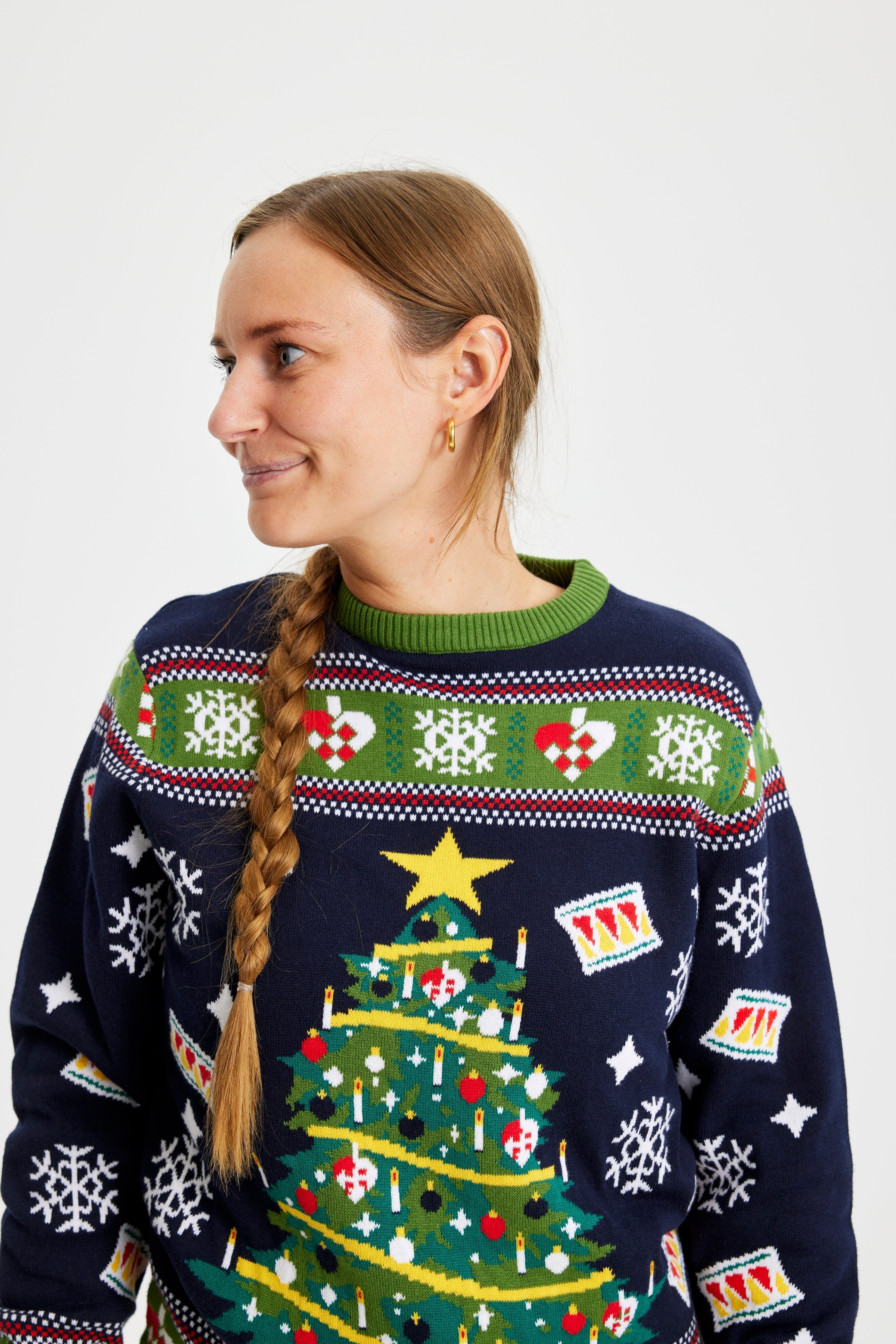 Une femme portant un pull bleu et vert avec un sapin de Noël.