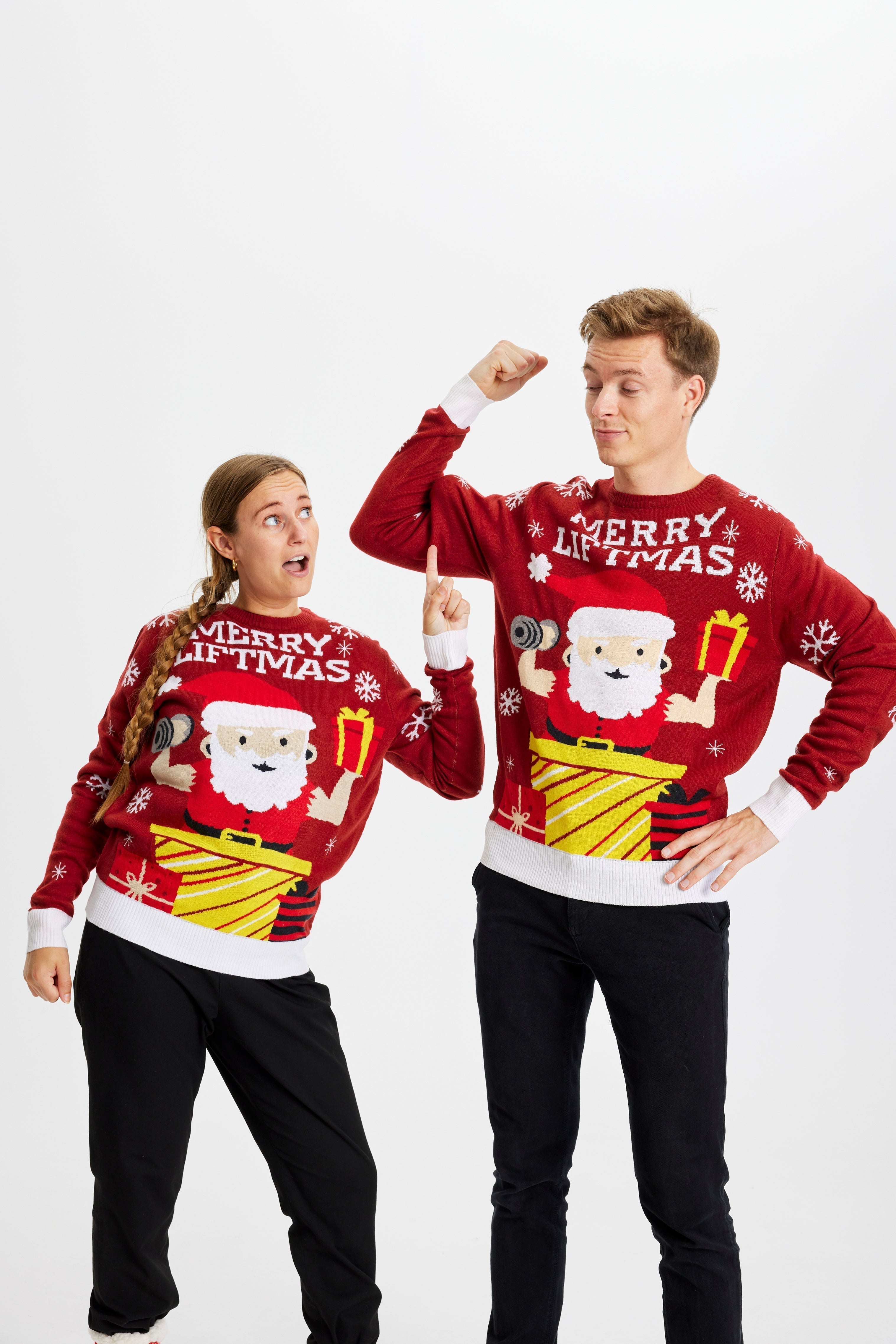 Un couple portant un pull de Noël rouge avec la citation 