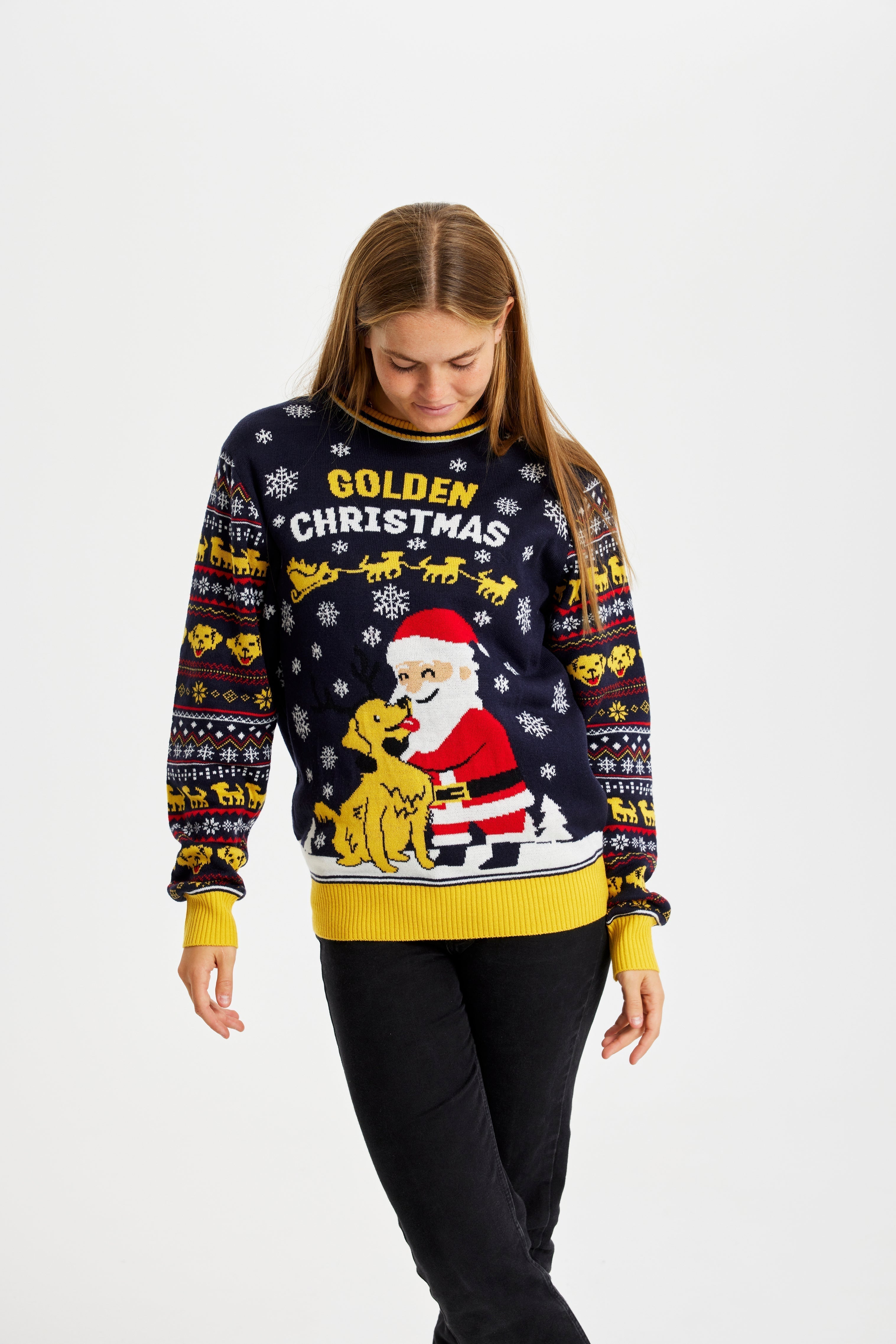 Une femme posant avec un pull de Noël jaune et noir portant l'inscription 