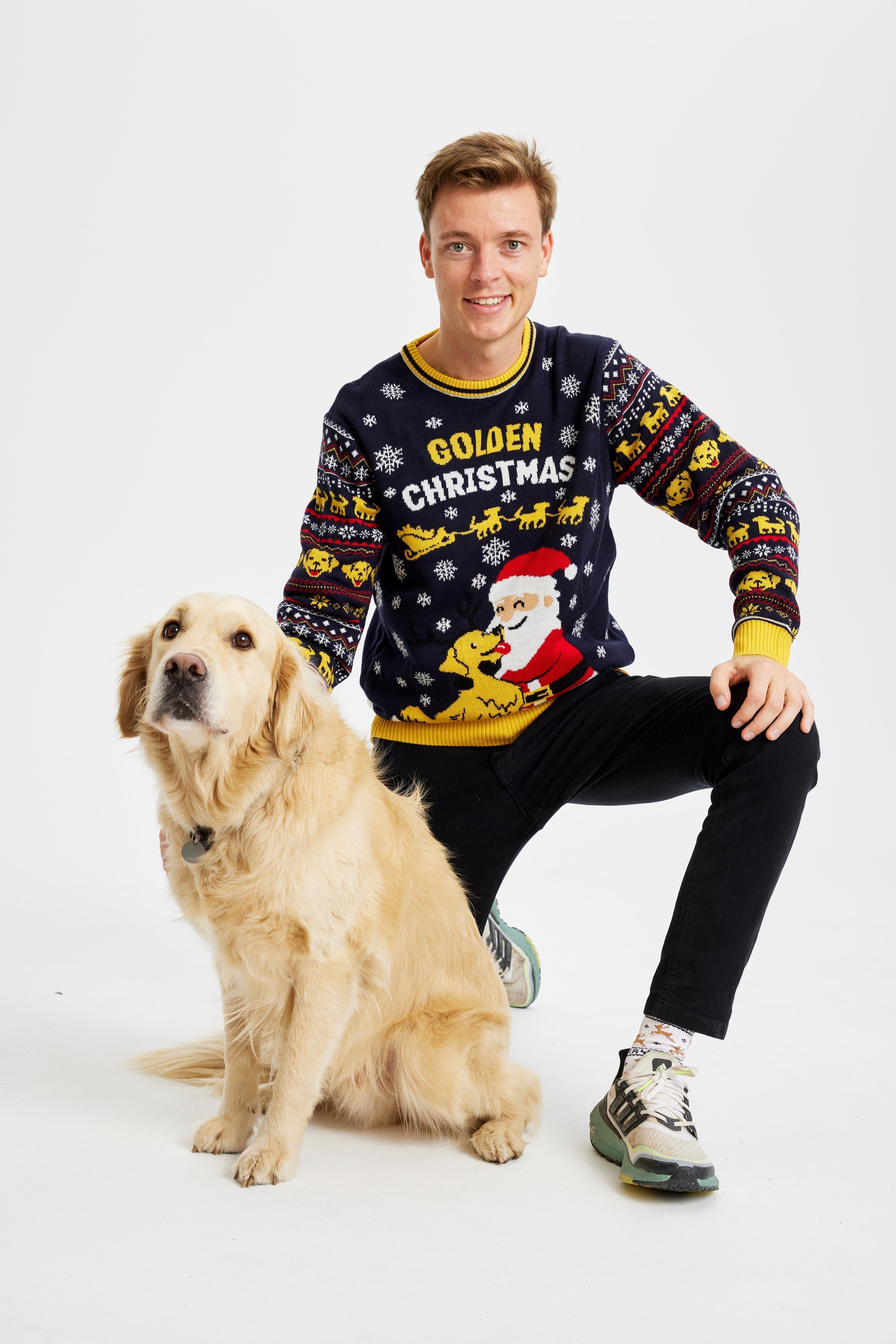 Un homme avec un chien portant un pull de Noël jaune et noir avec l'inscription 