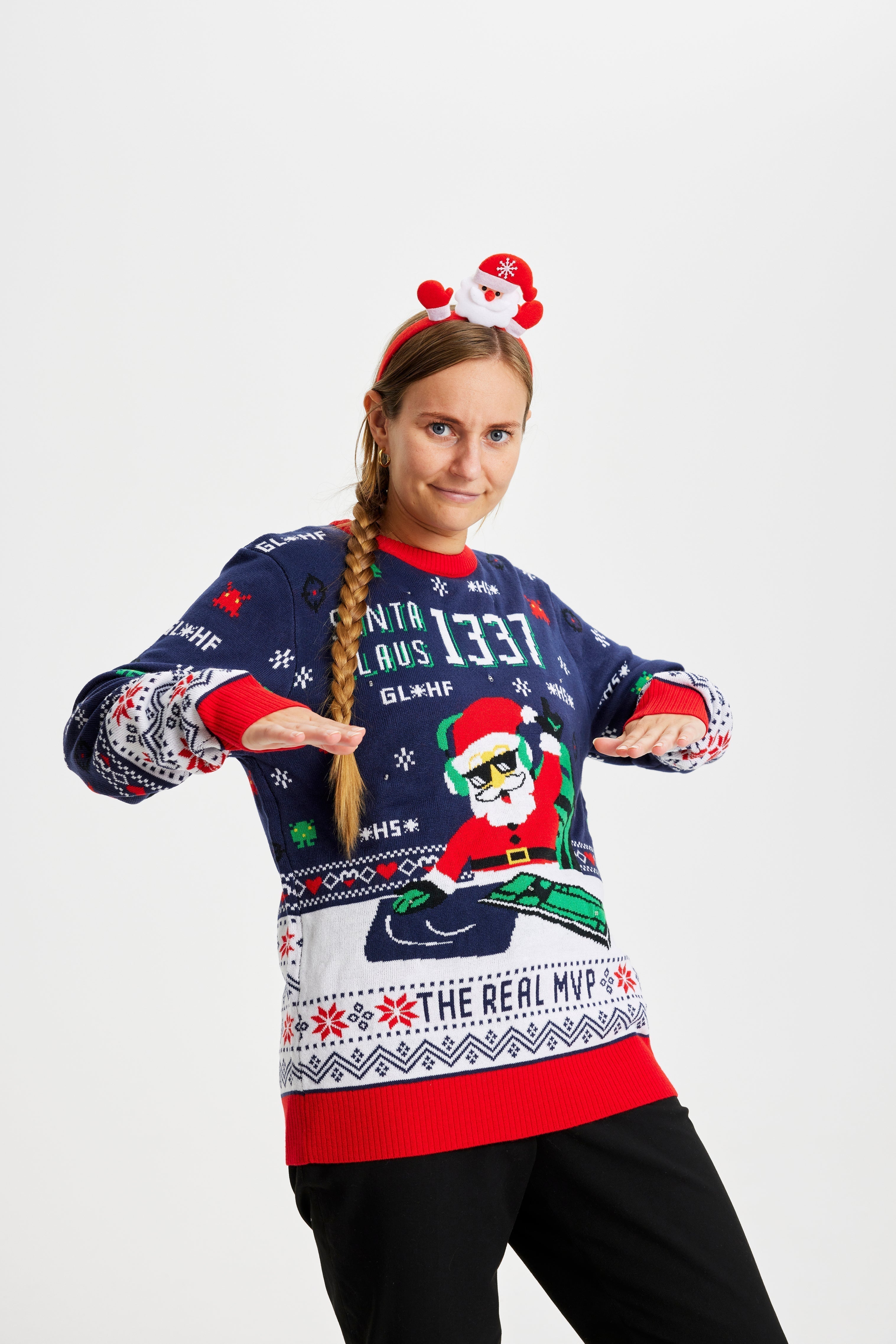 Une femme souriante portant un pull de Noël bleu et rouge avec un Père Noël et des lumières.