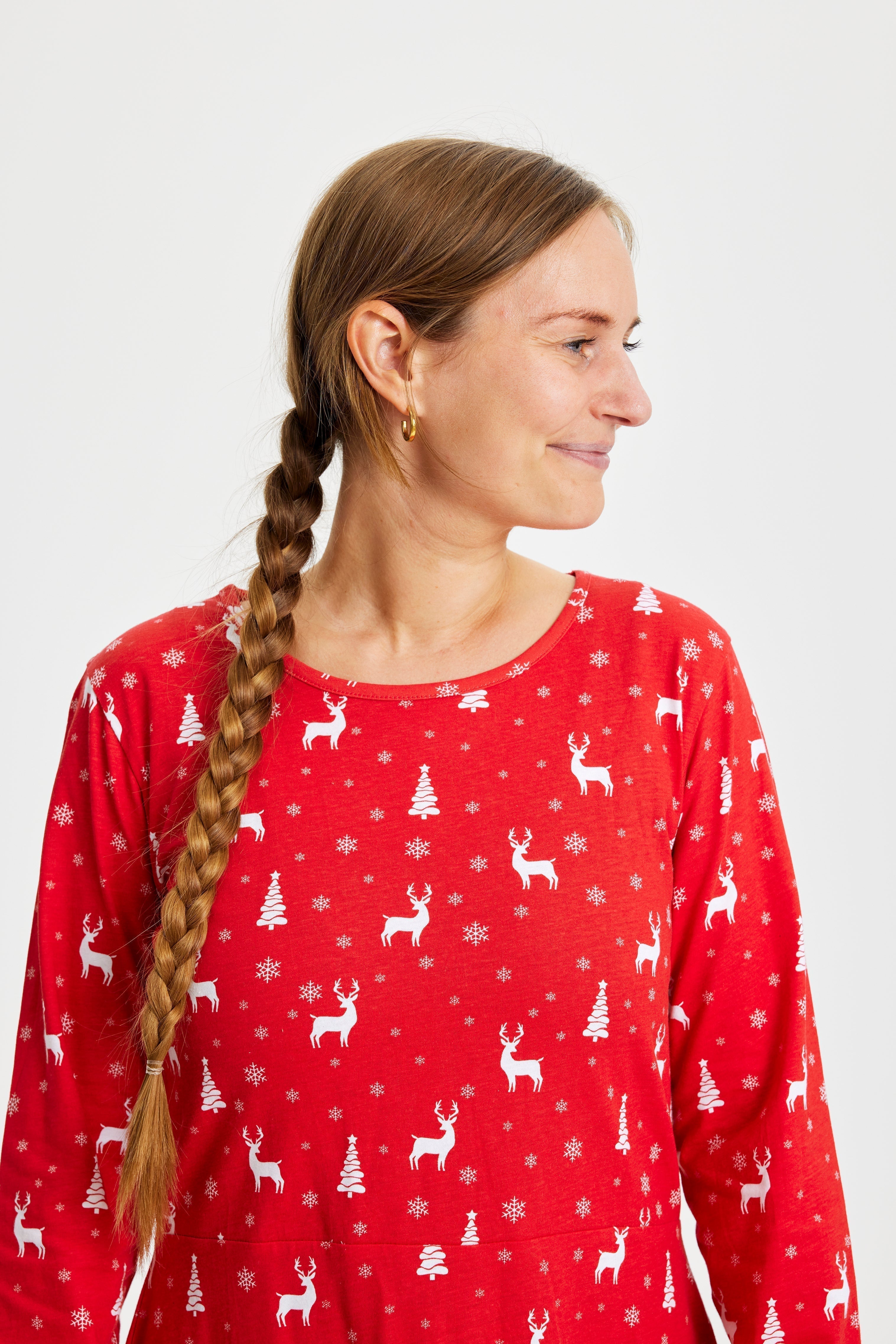 Une femme regardant de côté portant une robe de Noël rouge.