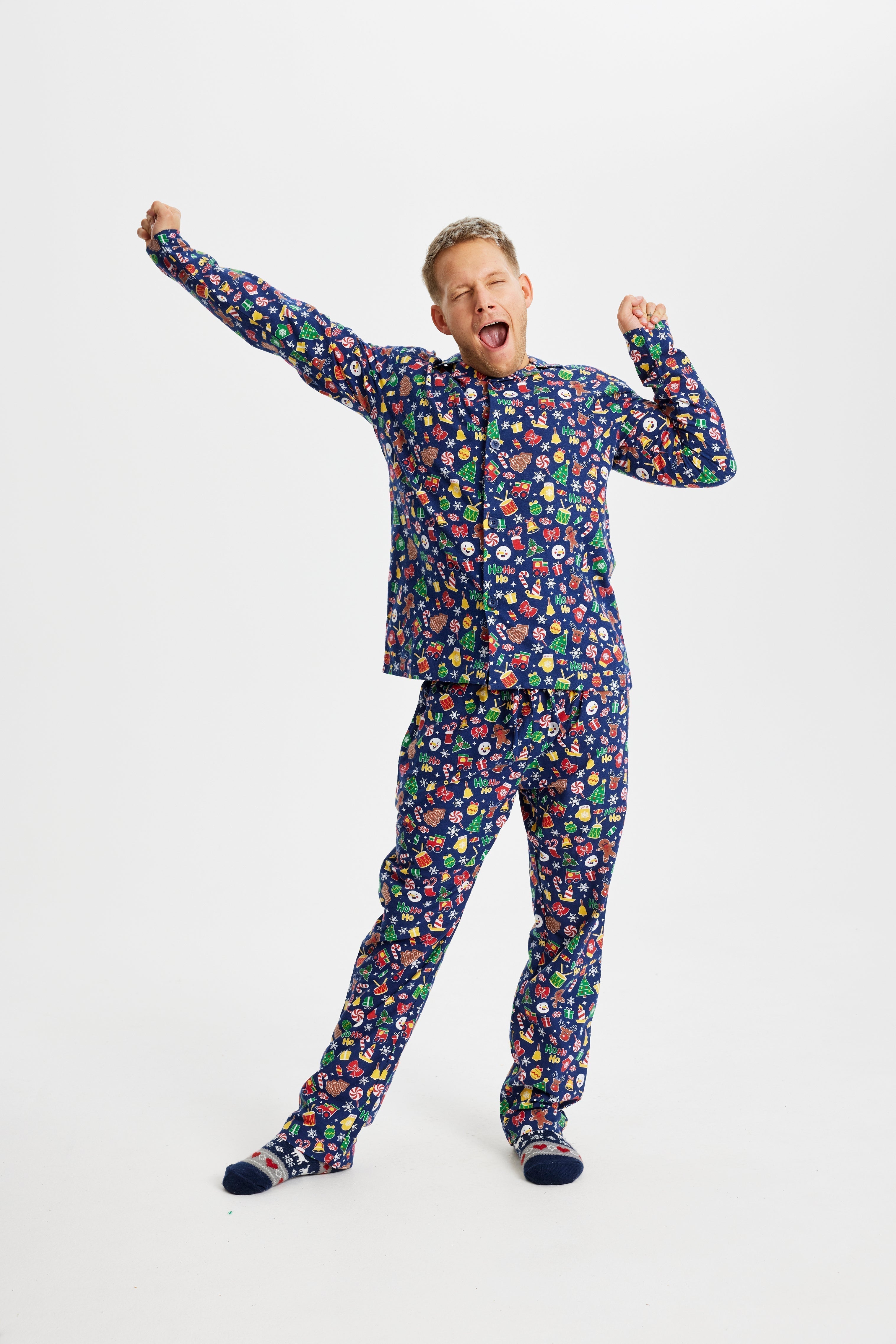 Un homme bâillant portant un pyjama bleu à imprimé de Noël.