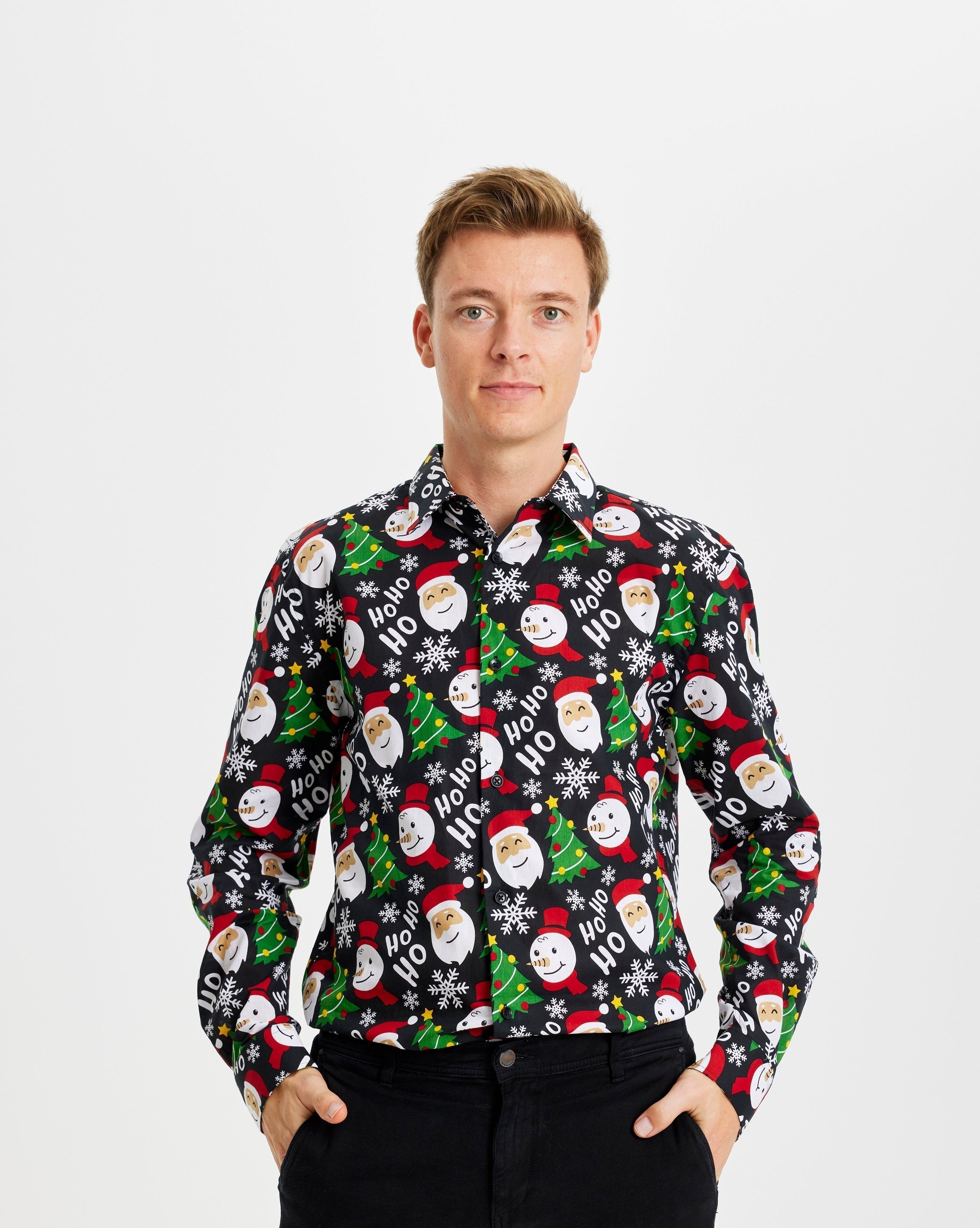 Un homme souriant portant une chemise de Noël noire à motifs.