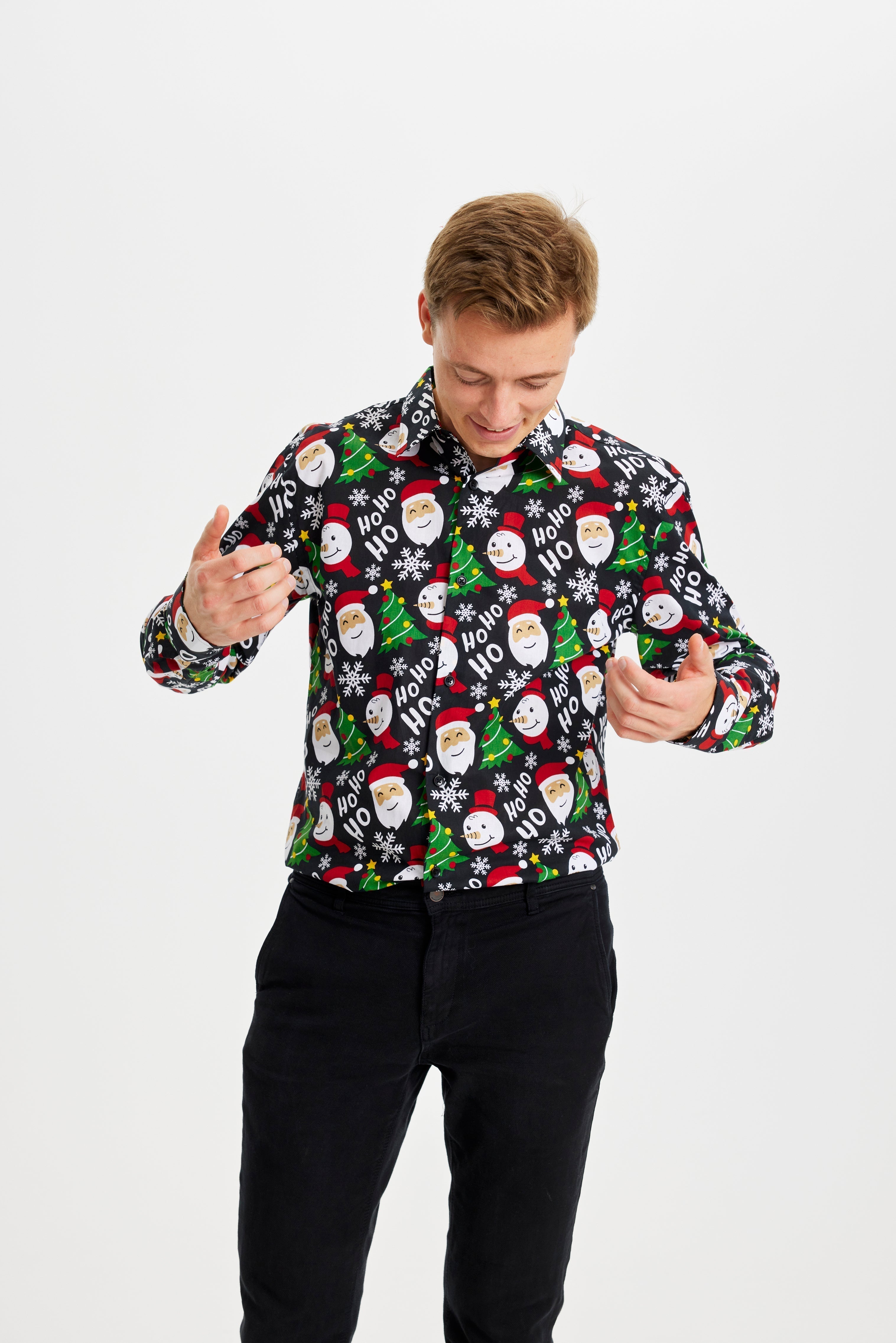 Un homme posant avec une chemise de Noël noire à motifs.