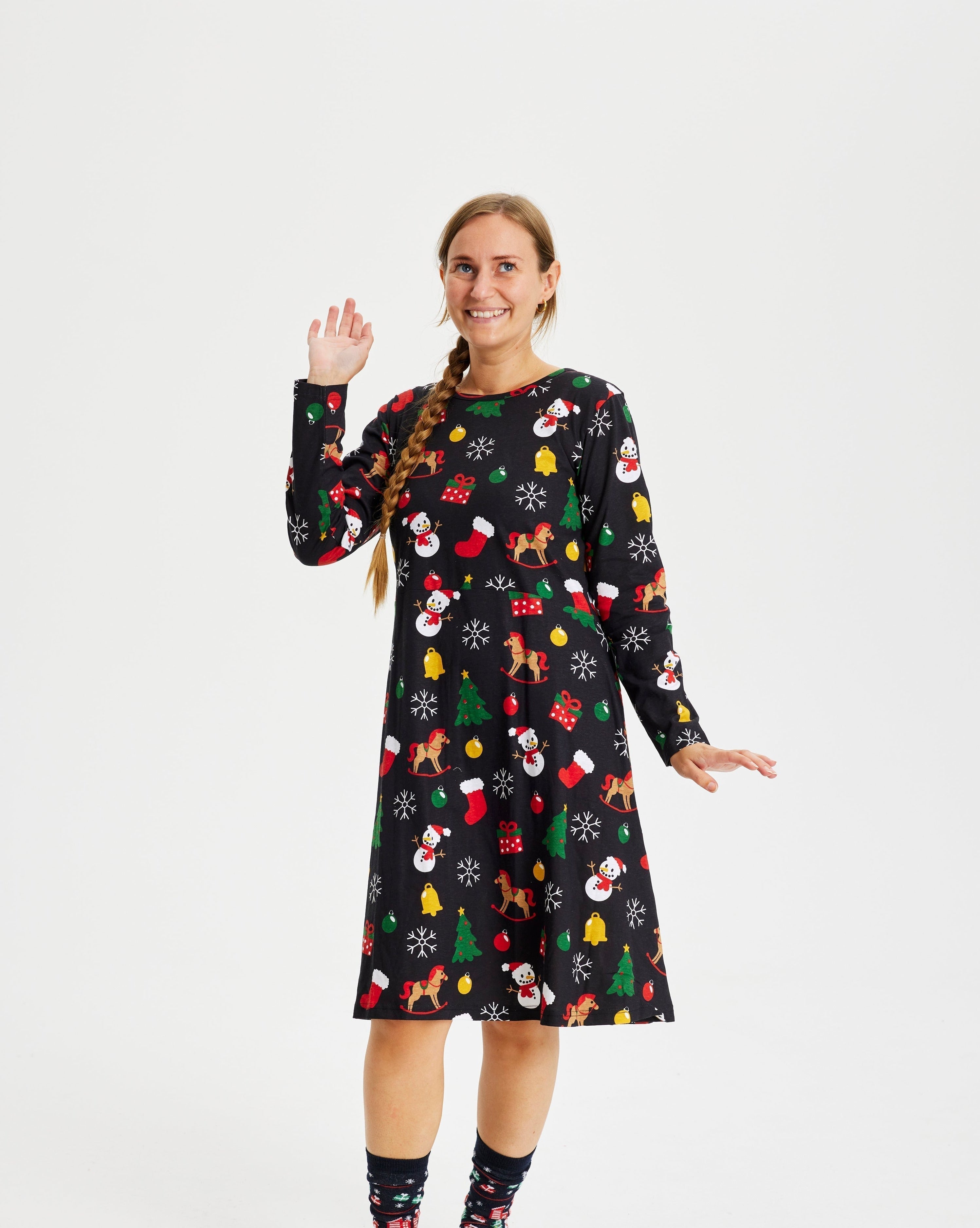 Une femme souriante portant une robe de Noël noire.